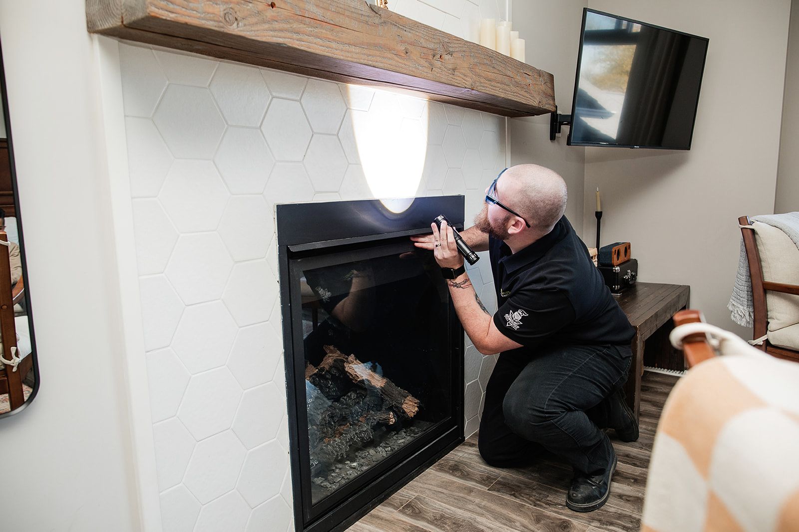 A man is kneeling down in front of a fireplace in a living room.