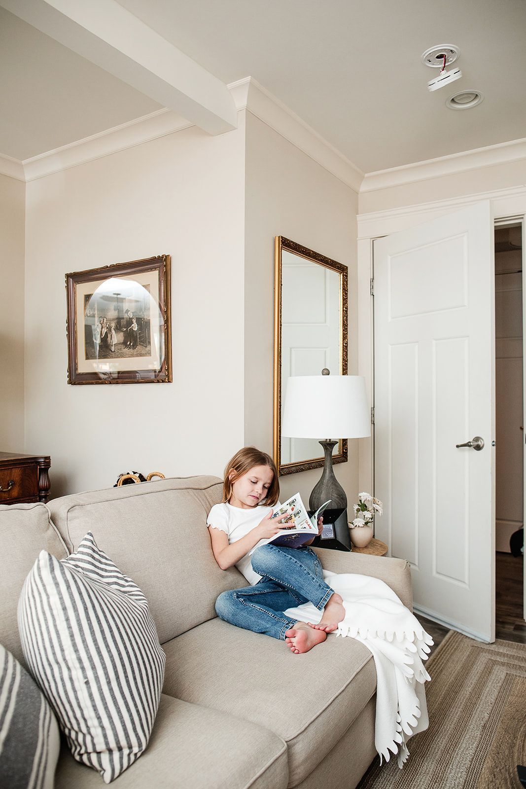 A little girl is sitting on a couch reading a book.