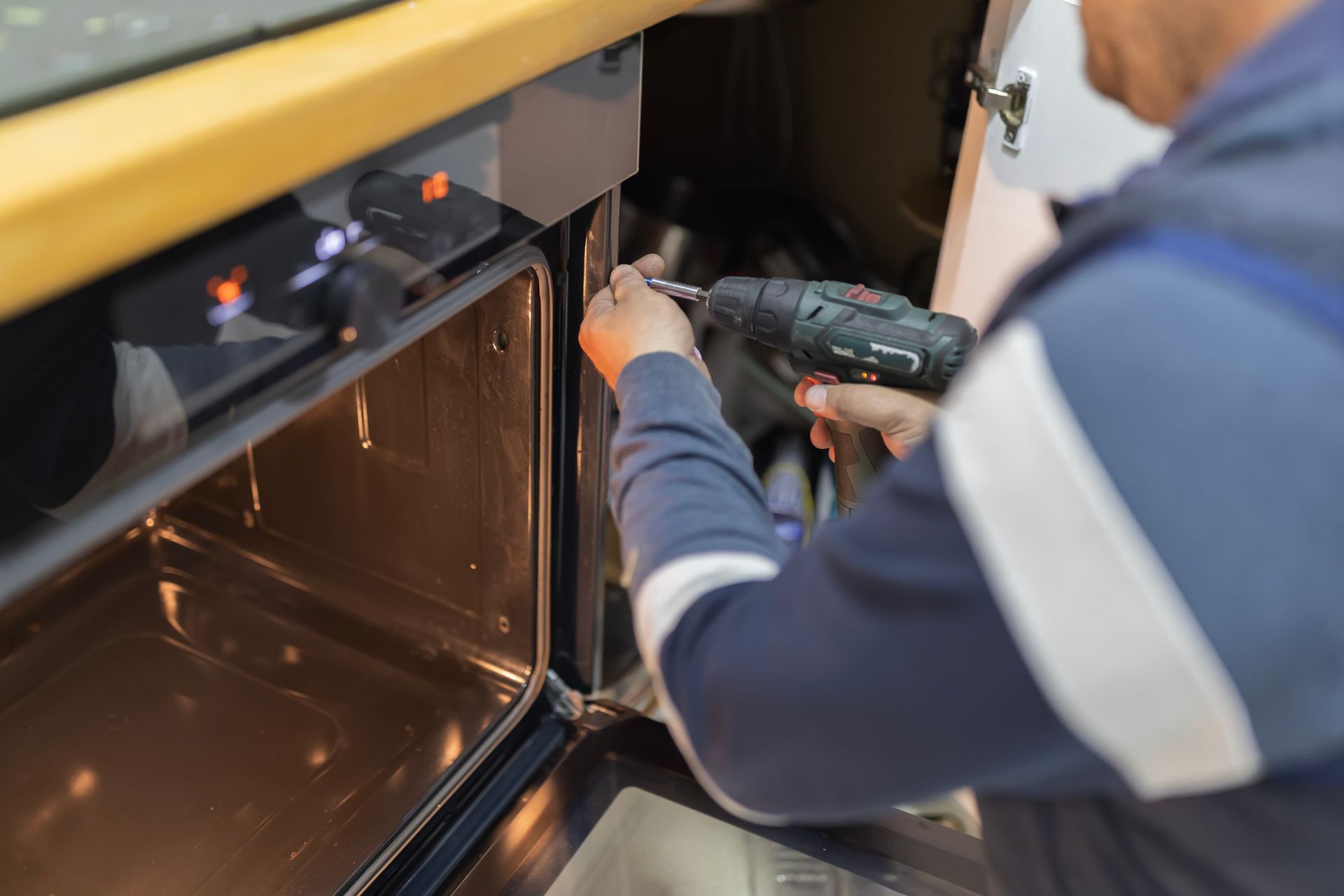 Technician in red gloves working on exposed electrical panel beside a window