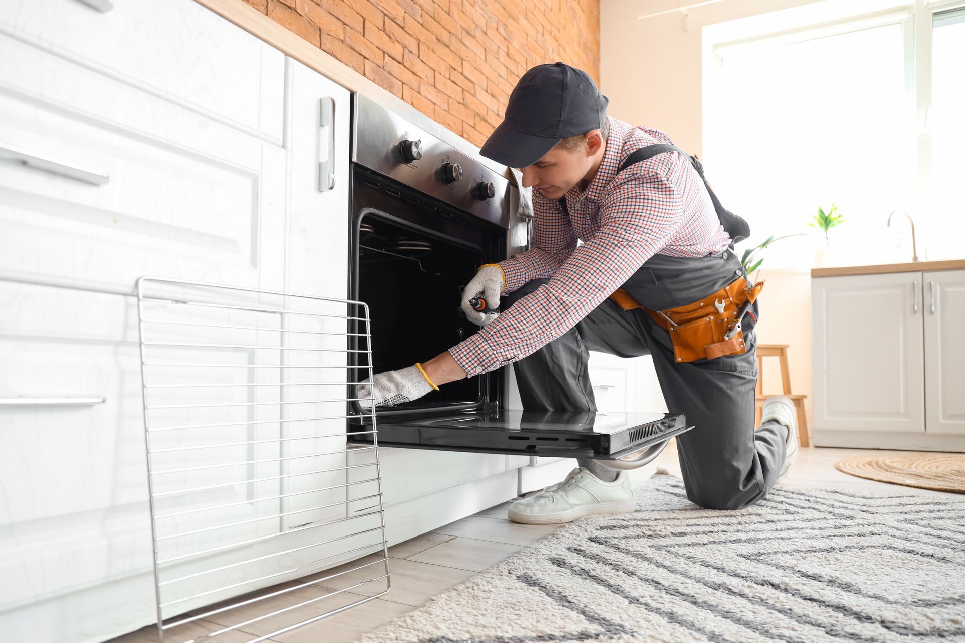 Technician repairing a built-in oven in a bright kitchen