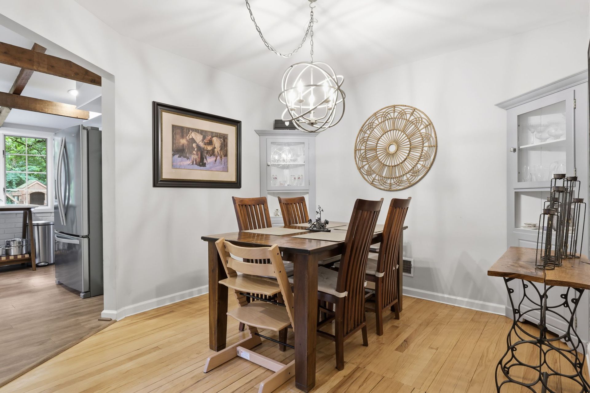 Bright dining room with wooden table, chairs, chandelier, and decorative wall art