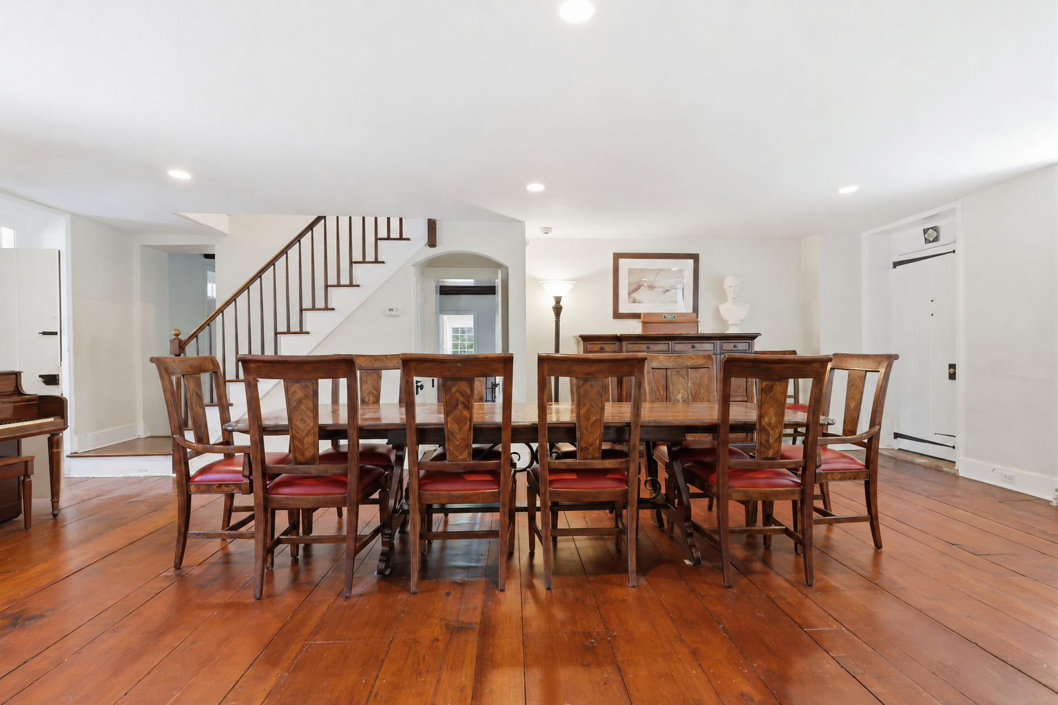 Dining room with long wooden table, chairs, and hardwood floors in a bright open-plan home