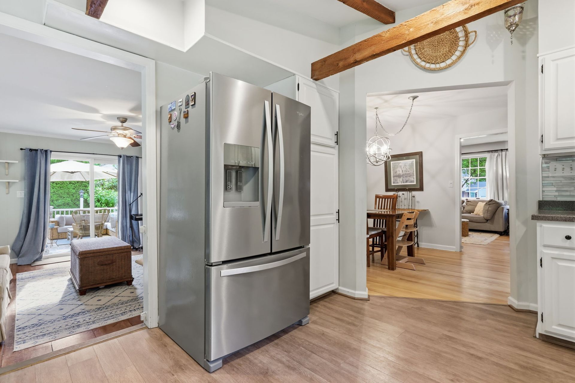 Modern kitchen with stainless steel refrigerator, hardwood floors, and a view into the dining and living areas