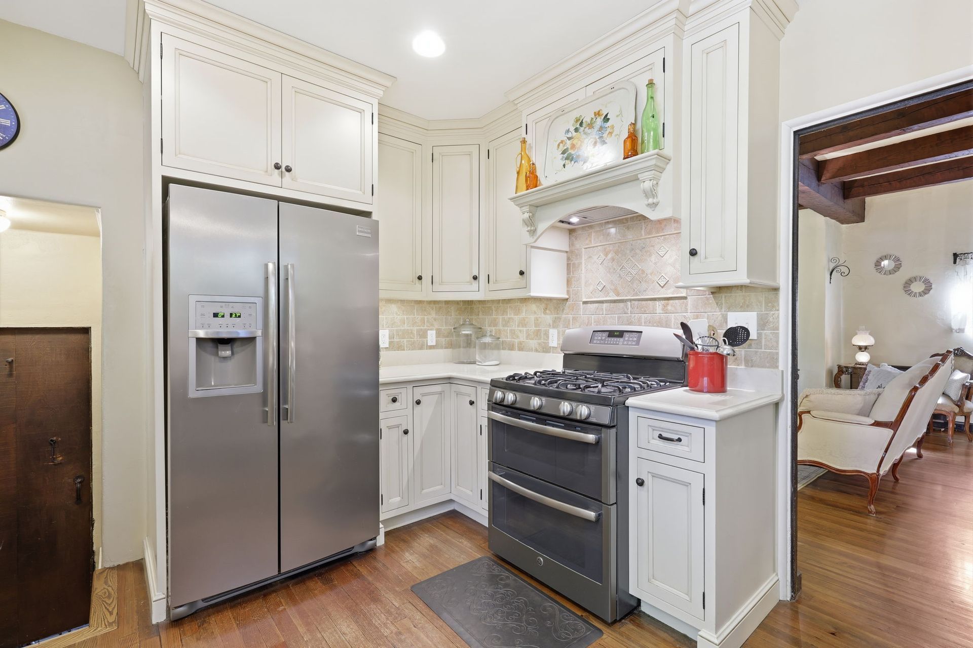 Bright kitchen with stainless steel appliances, white cabinets, and a gas range under a decorative hood.