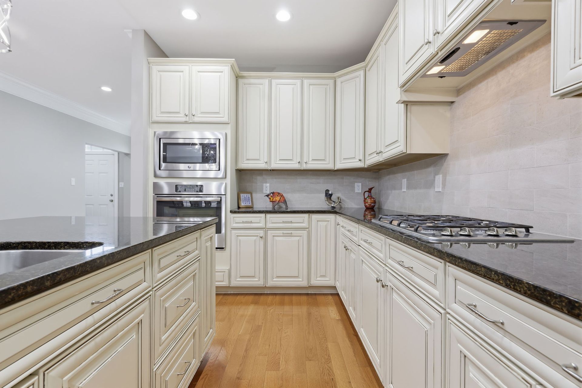 Bright modern kitchen with white cabinets, stainless appliances, and wood floors