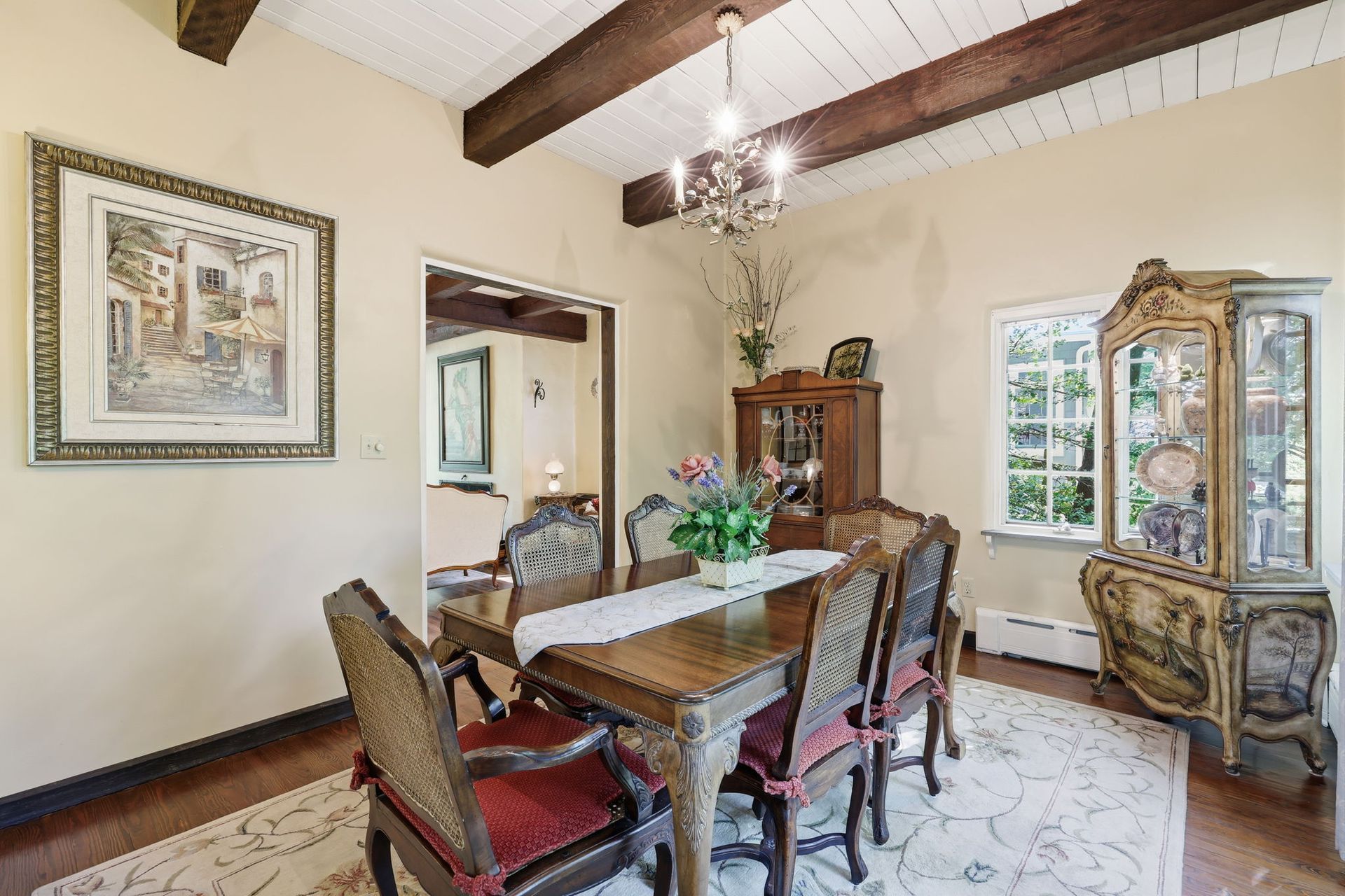 Elegant dining room with a wooden table, upholstered chairs, chandelier, and glass-front display cabinet