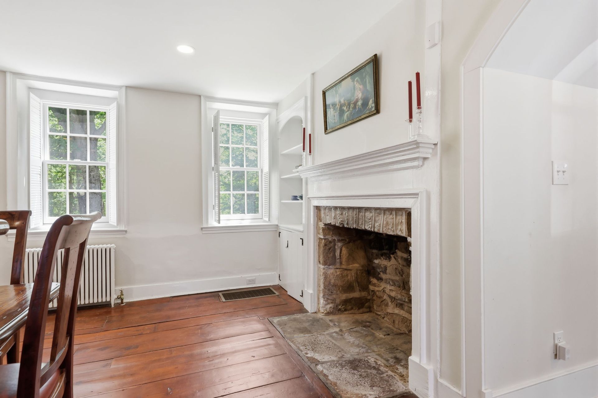 Bright dining room with wood floor, fireplace, and two windows.