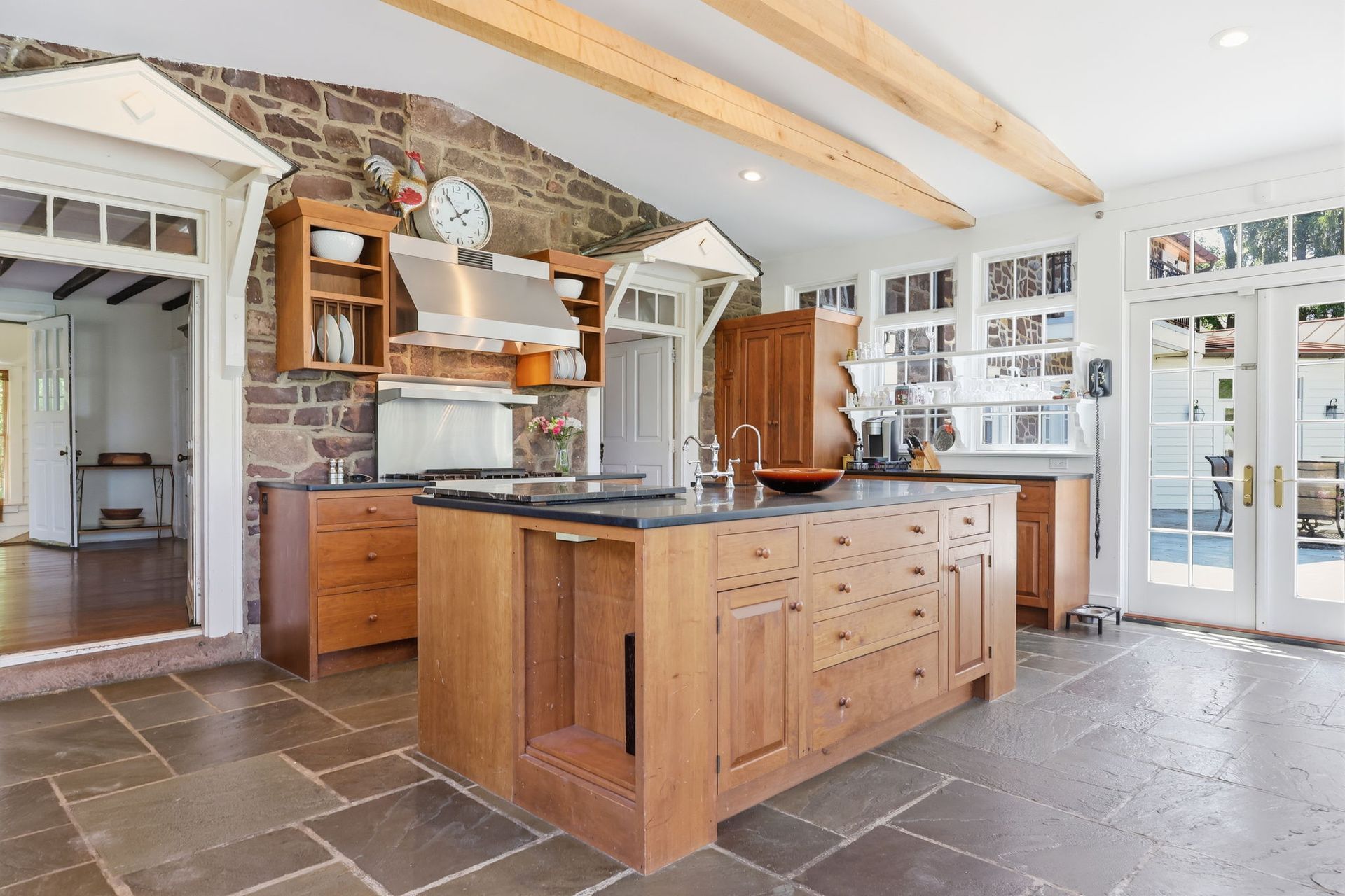 Modern kitchen with wood island, stone floor, vaulted ceiling, and glass doors