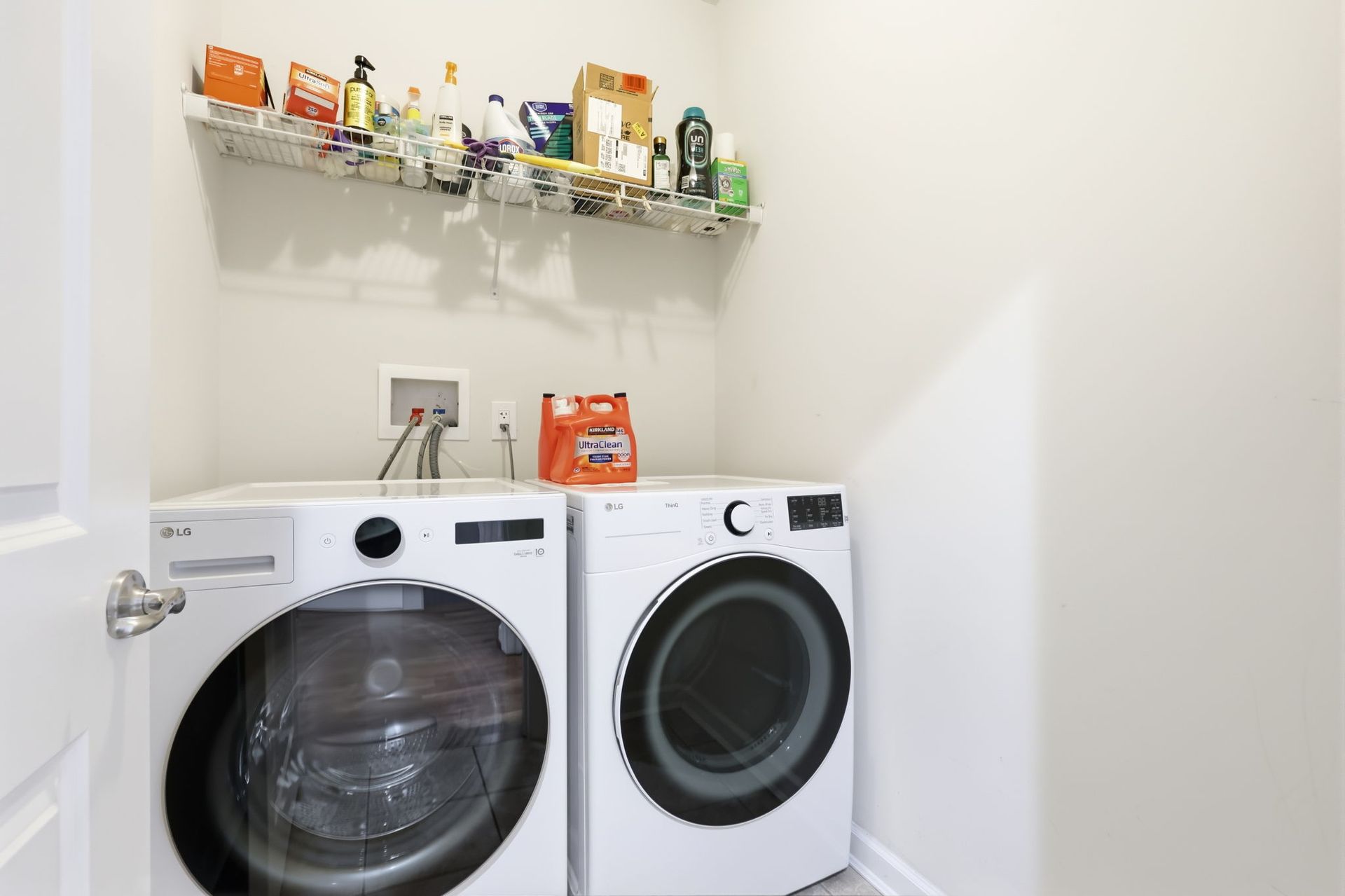 Laundry room with a washer and dryer beneath wall shelves of cleaning supplies