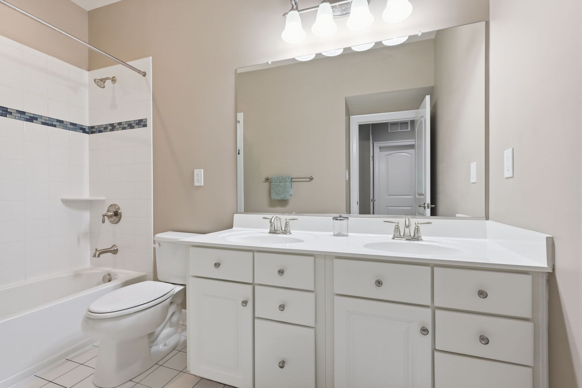 Bright bathroom with white vanity, large mirror, and bathtub with shower curtain
