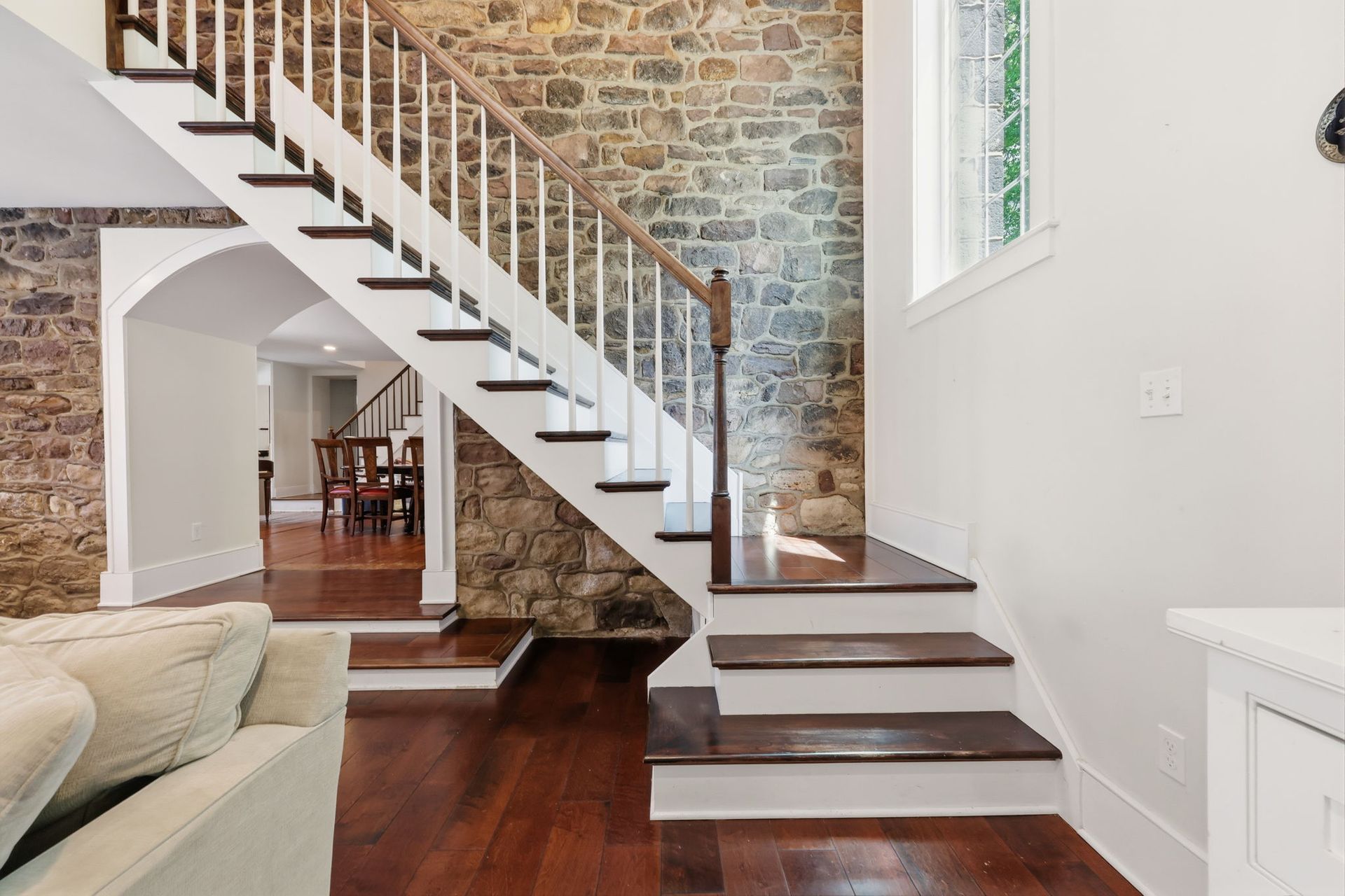 Modern home interior with floating staircase, exposed brick wall, and hardwood floors
