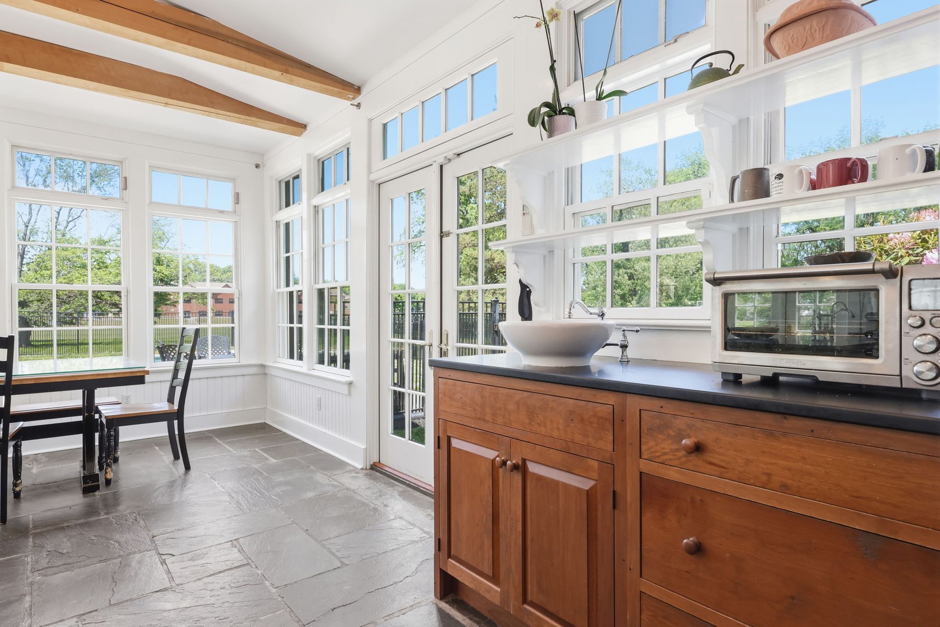 Bright kitchen with wood cabinets, black countertop, large windows, and a dining table by the window.