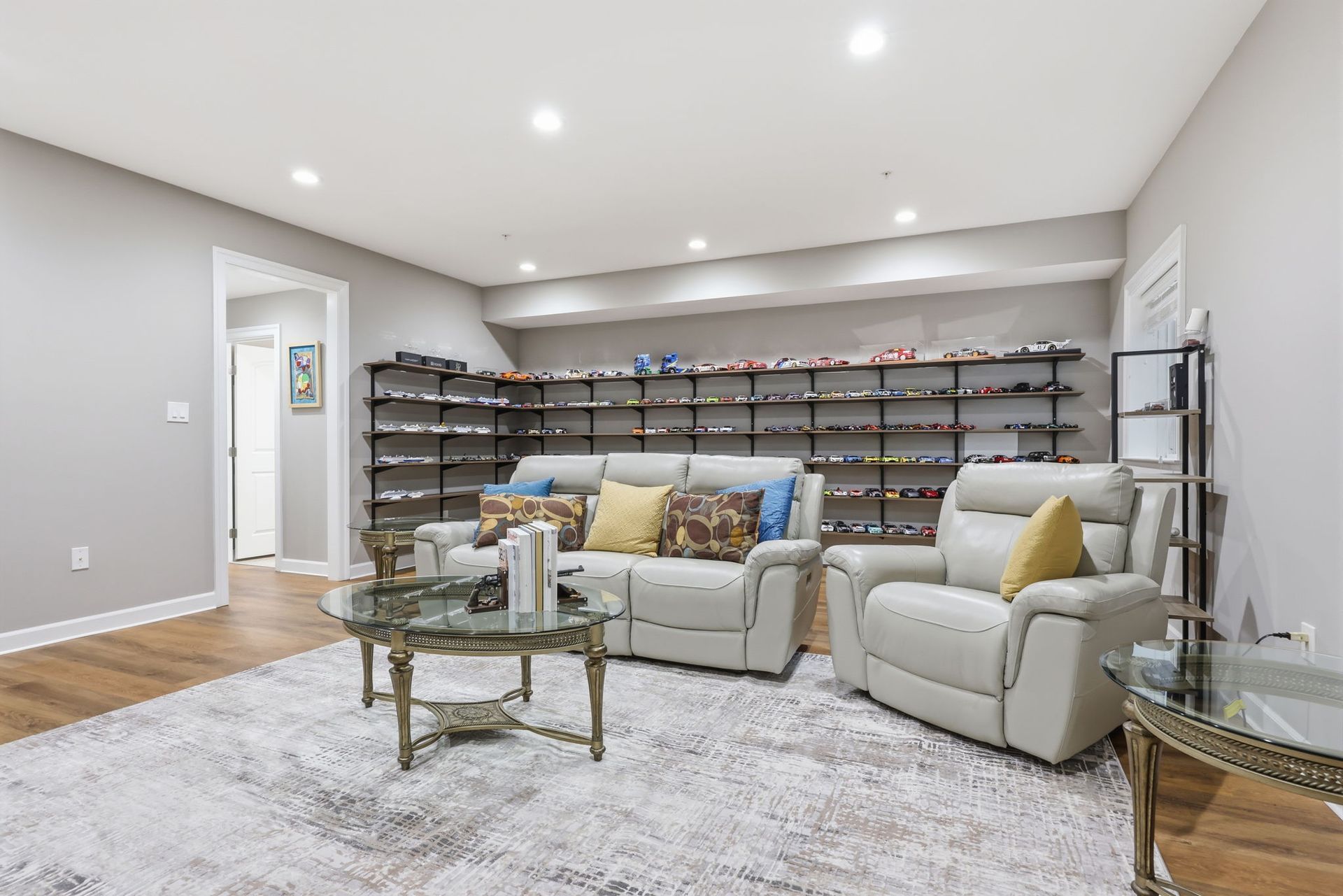 Bright modern living room with beige sofa, armchair, glass coffee table, and wall of shoe shelves