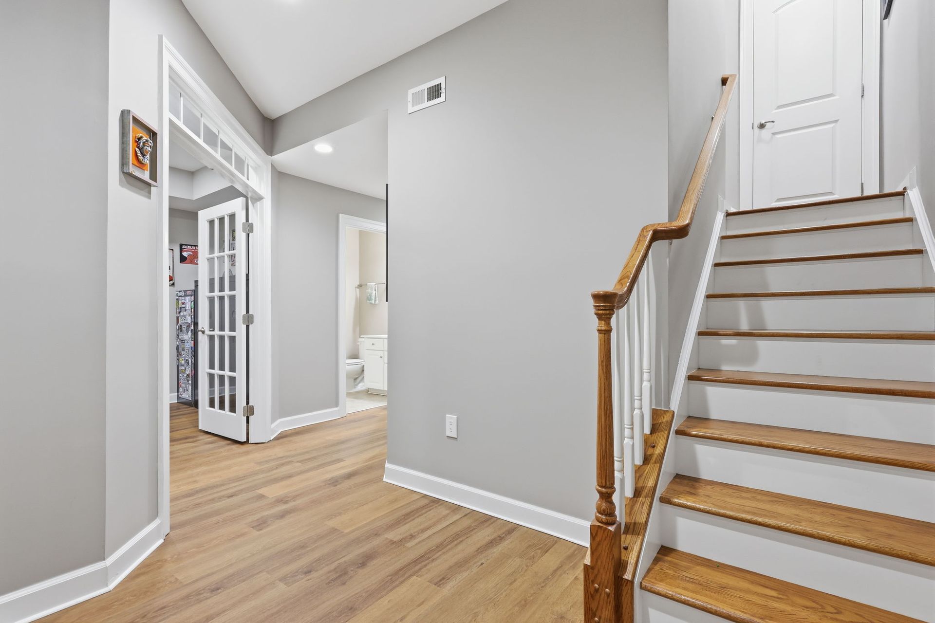 Bright hallway with wood stairs, gray walls, and white doors in a modern home.