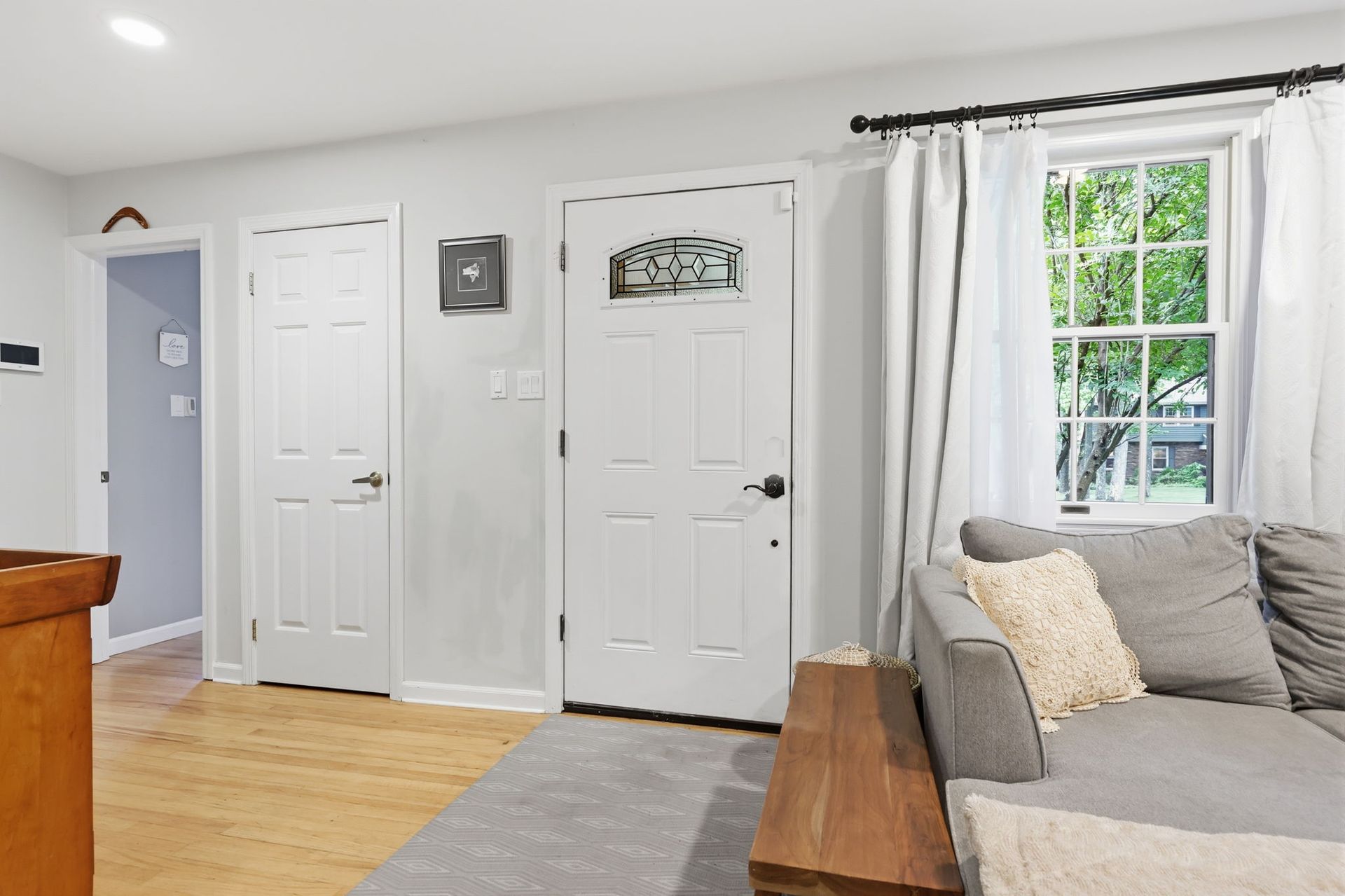 Bright living room with white doors, gray sofa, and a window with sheer curtains