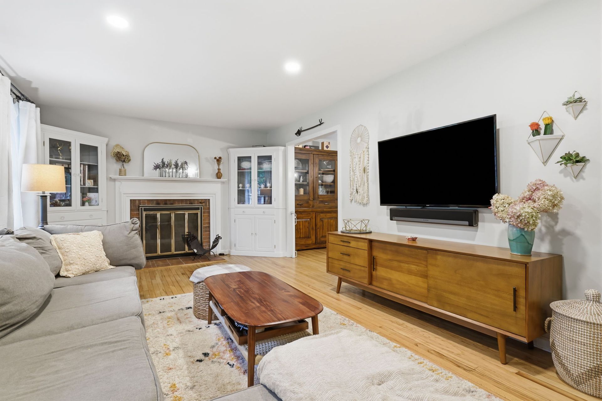 Cozy living room with fireplace, large TV, wooden console, and light gray sofa on a rug.