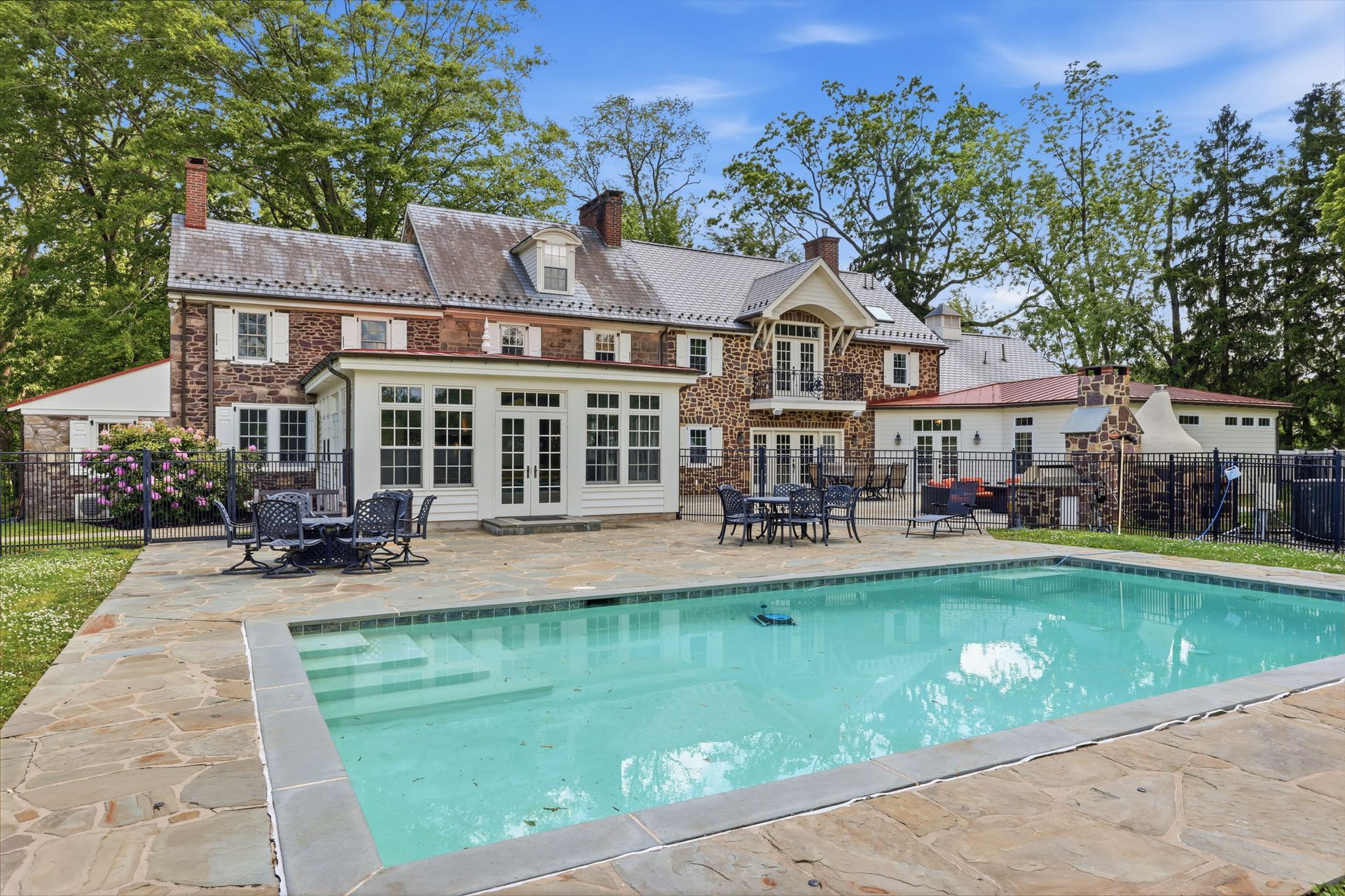 Large house with a backyard swimming pool and patio furniture on a sunny day