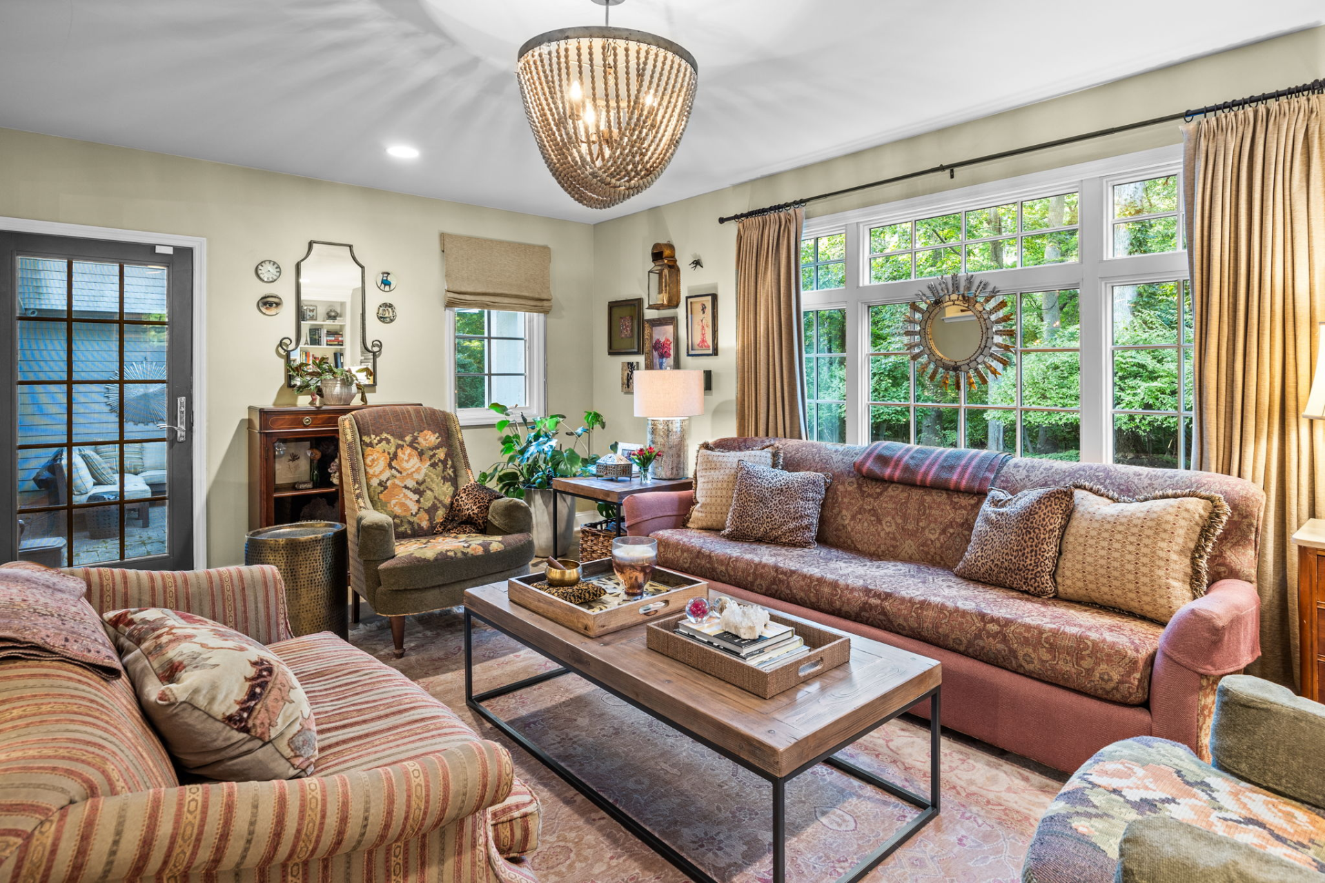 Cozy living room with floral patterned furniture, large window, and ornate chandelier.