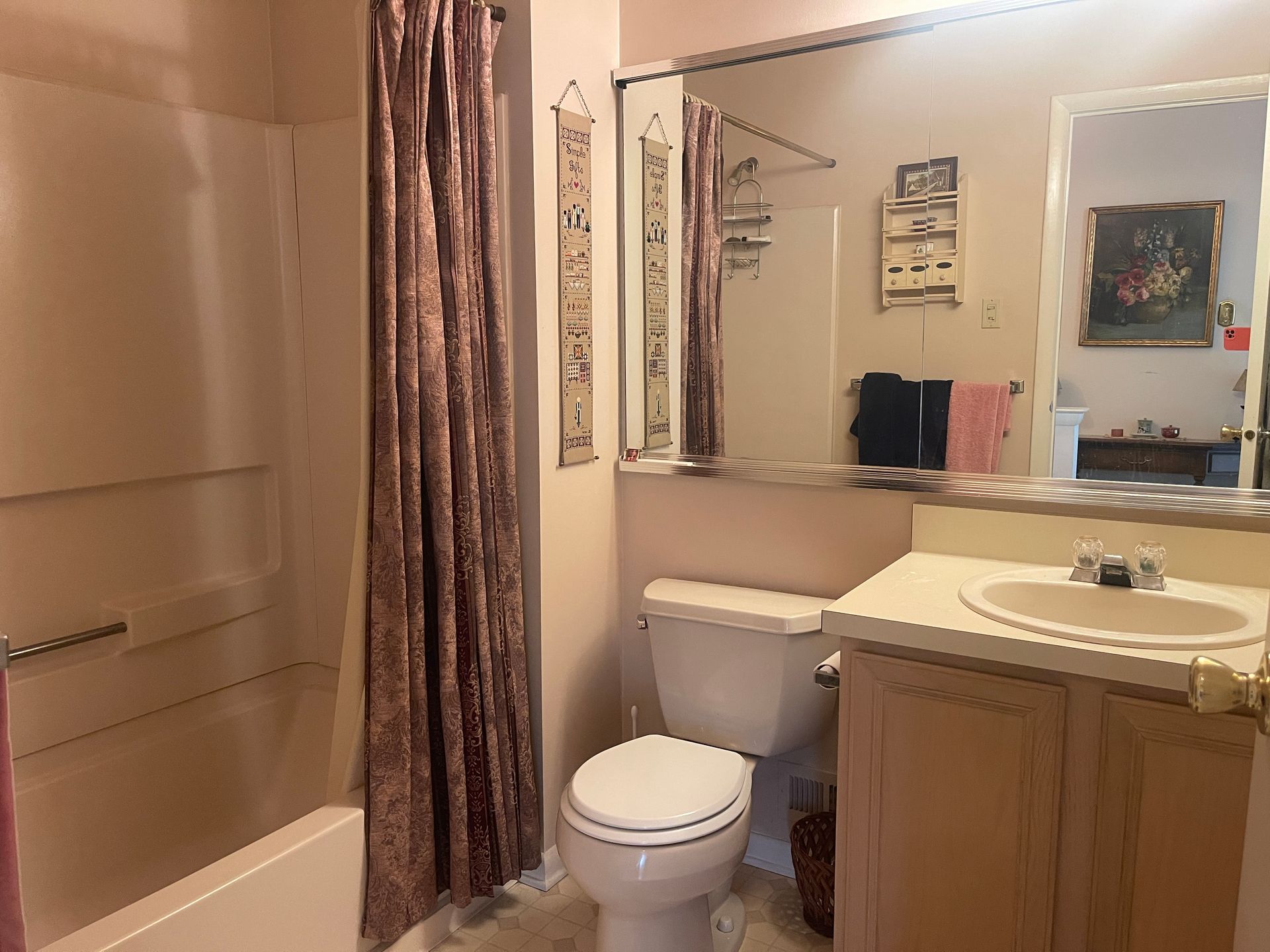 Bathroom with beige tub, toilet, sink, mirror, and brown shower curtain