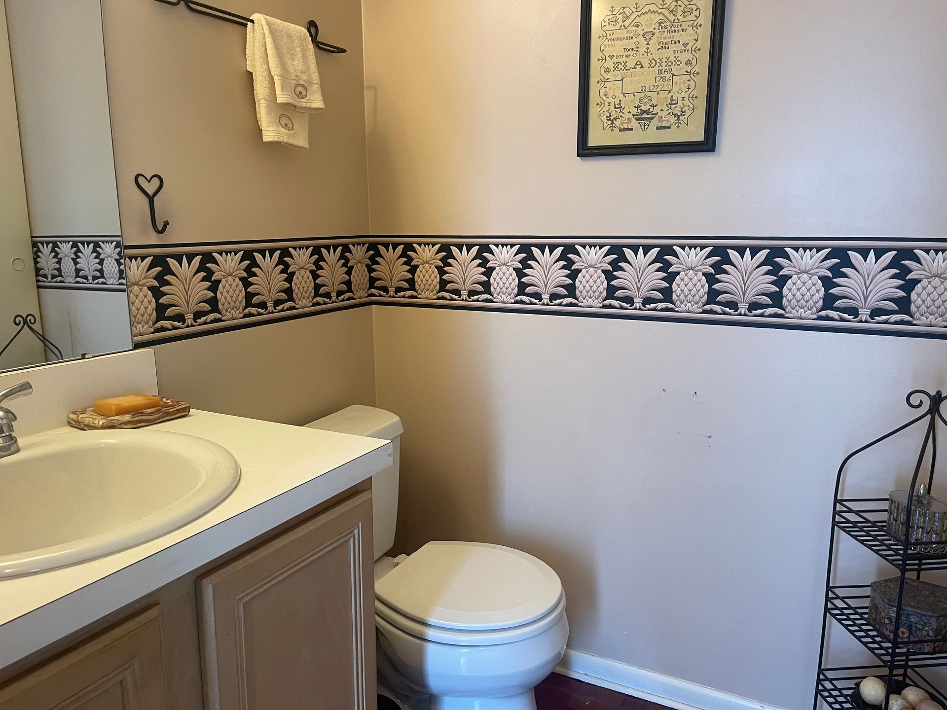Small bathroom with sink, toilet, towel rack, and black decorative border wallpaper.