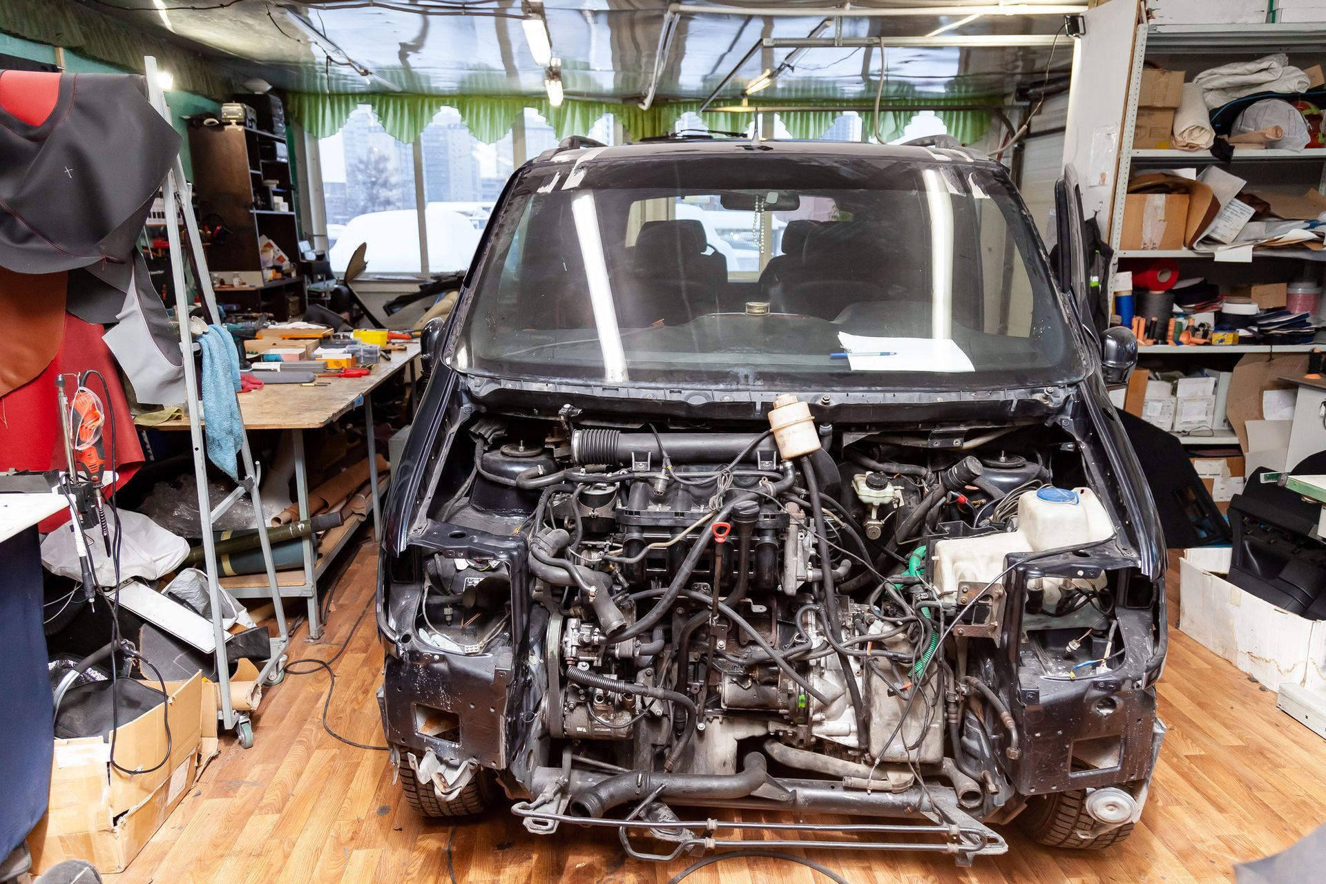 Furgone nero in riparazione in officina, parte anteriore smontata, motore esposto.