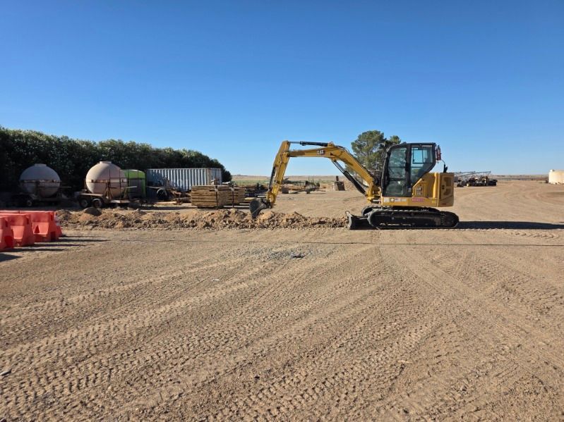 Yellow excavator on a gravel construction site under a clear blue sky