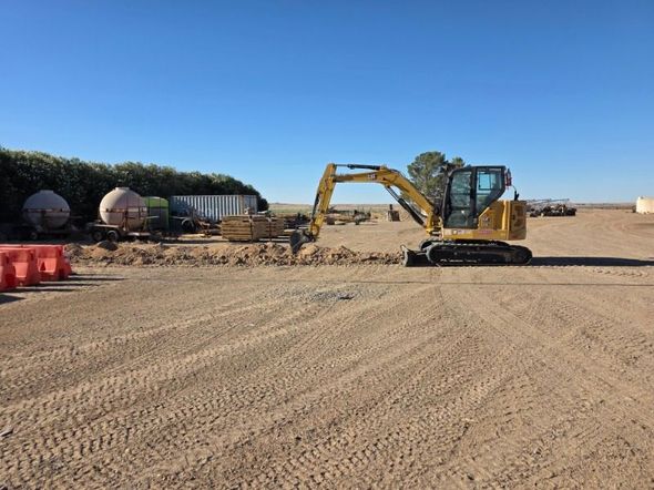 Yellow excavator on a gravel construction site under a clear blue sky