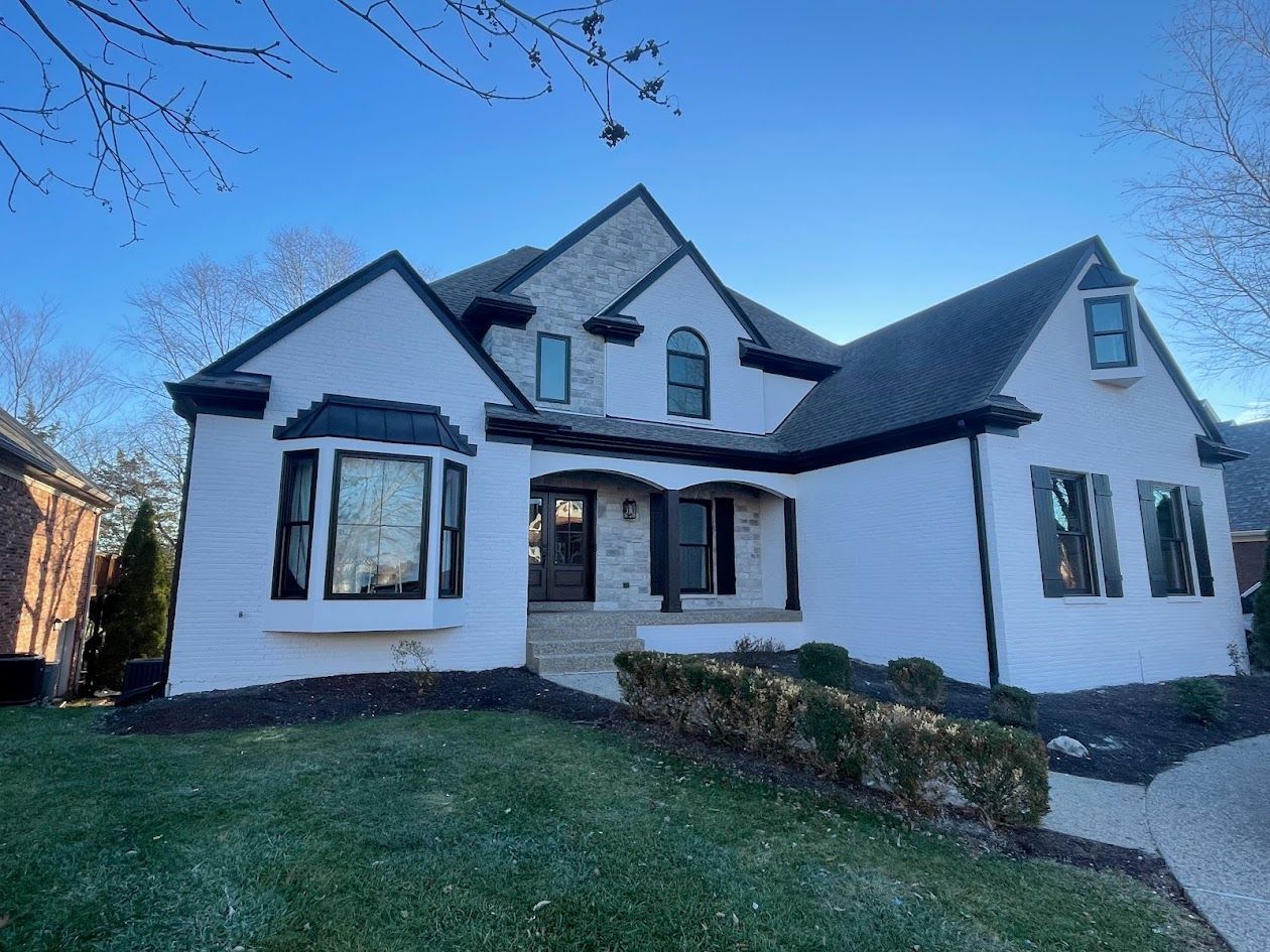 White house with black trim, a dark roof, and arched windows.