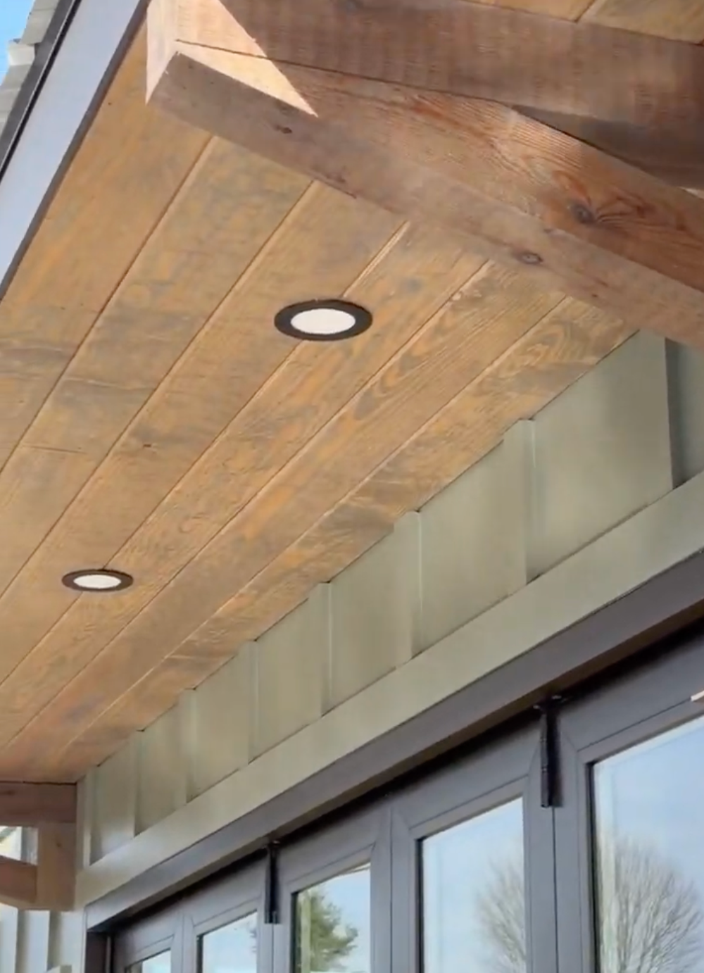 Wood-paneled overhang with recessed lights above glass storefront doors