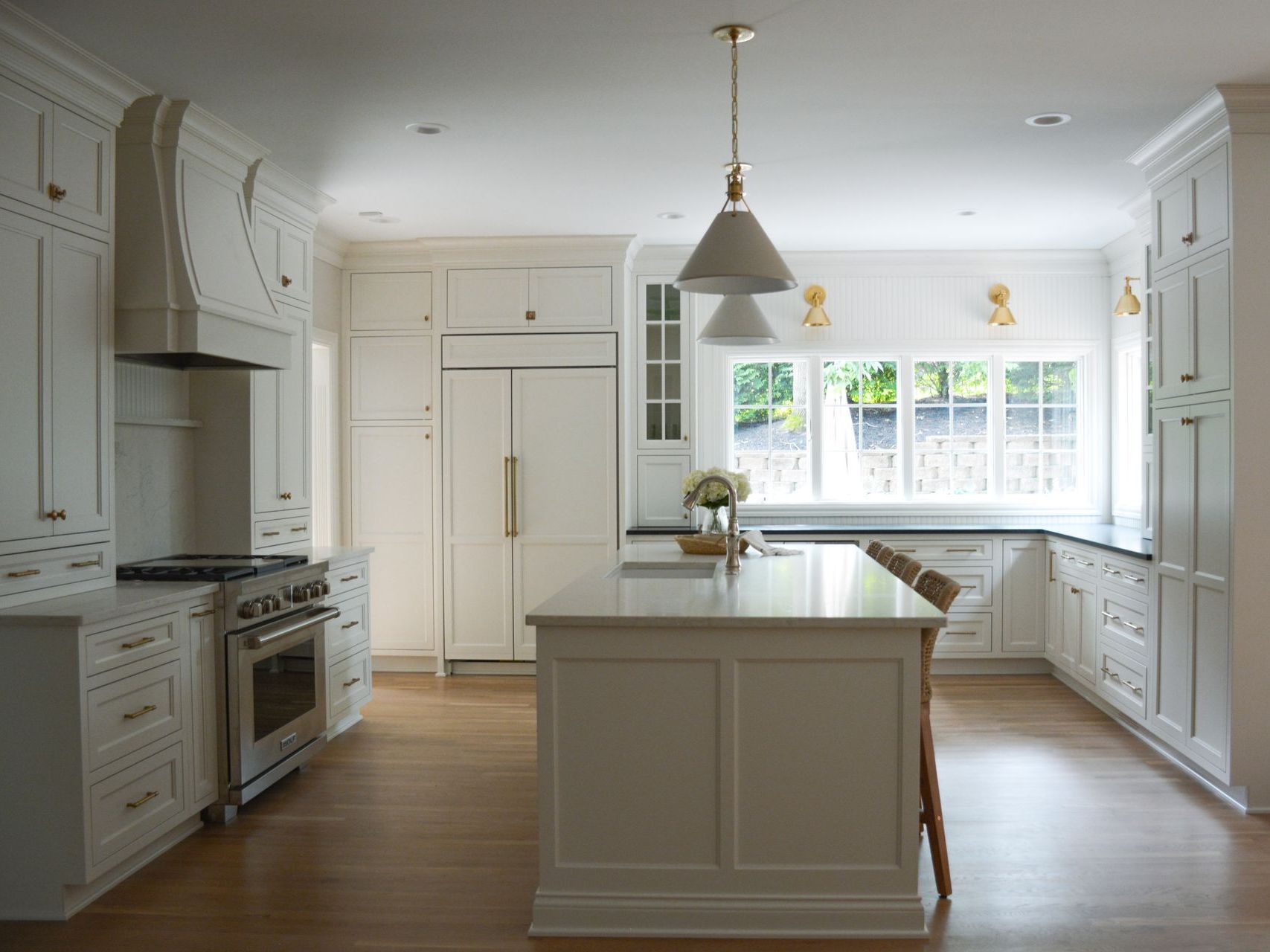 White kitchen with island, cabinets, range, and hardwood floor.