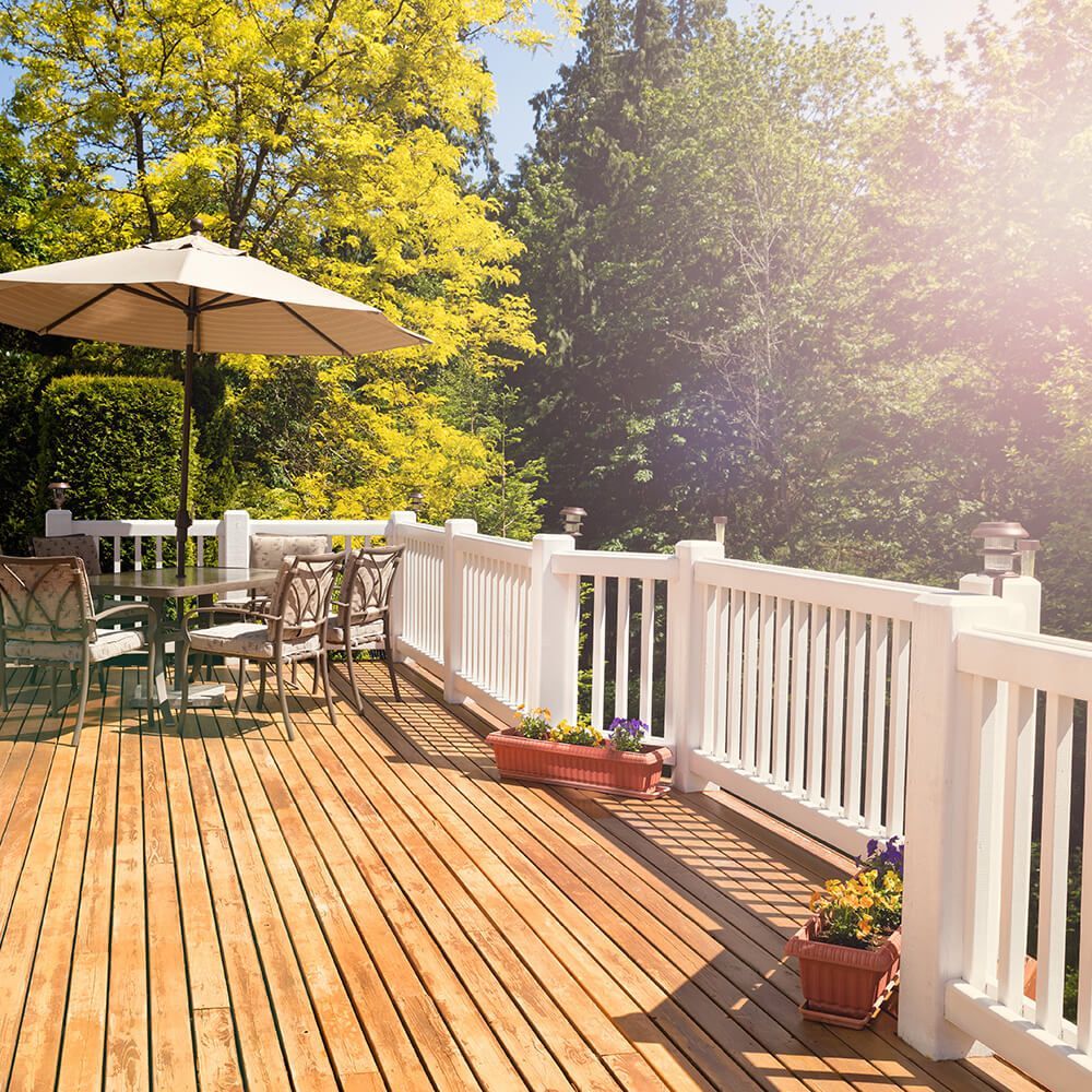 A wooden deck with a table and chairs and an umbrella.