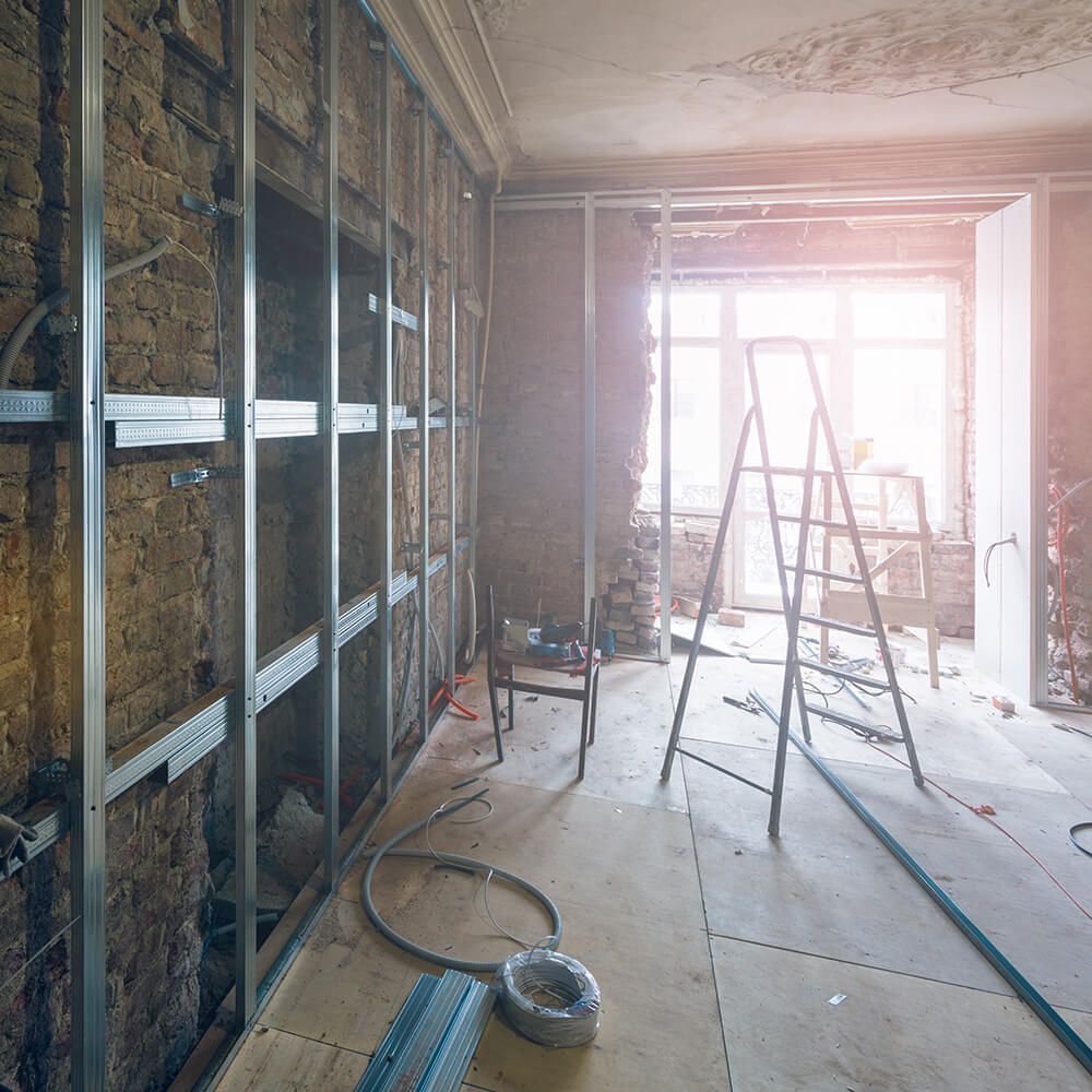 A room under construction with a ladder and a chair.