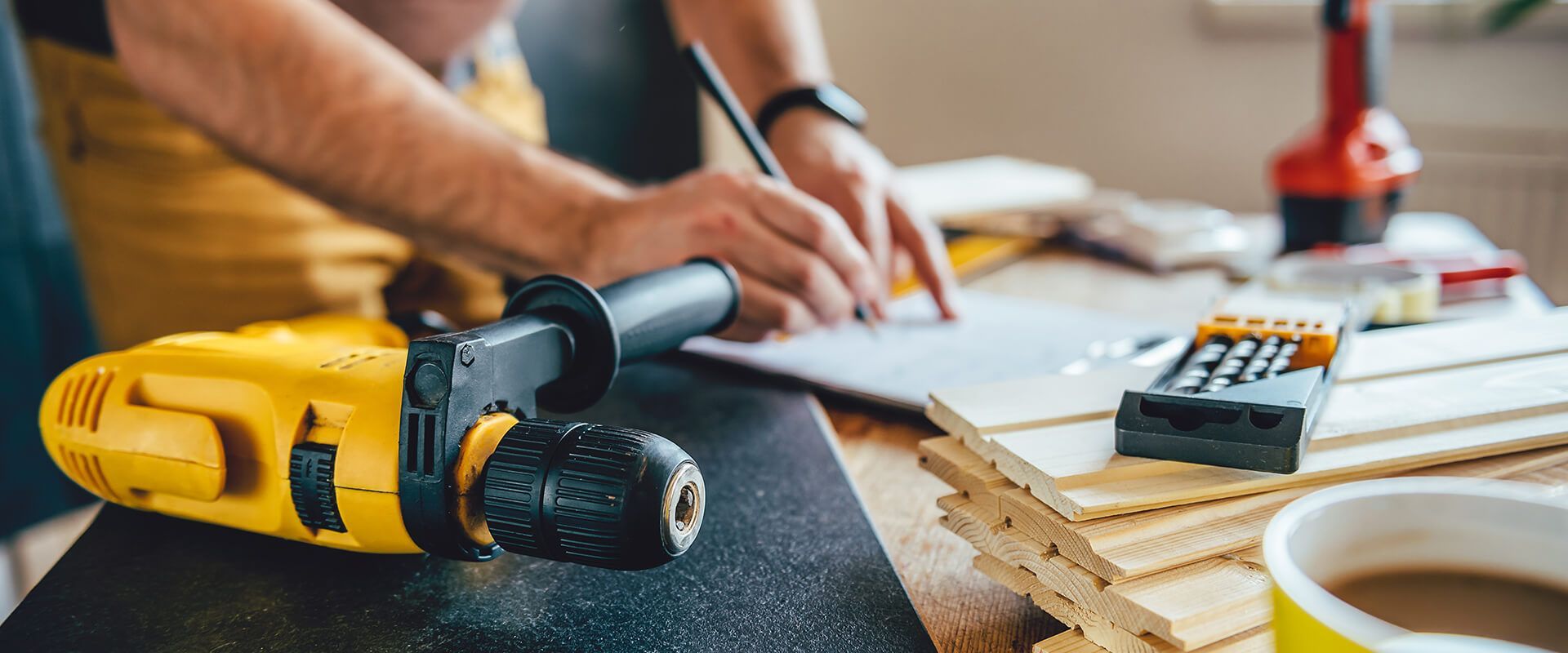 A man is using a drill to drill a hole in a piece of wood.