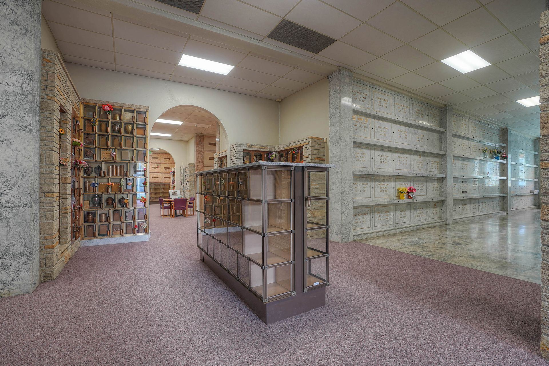 Empty indoor retail space with glass display cases, carpeted floor, and white walls under bright ceiling lights