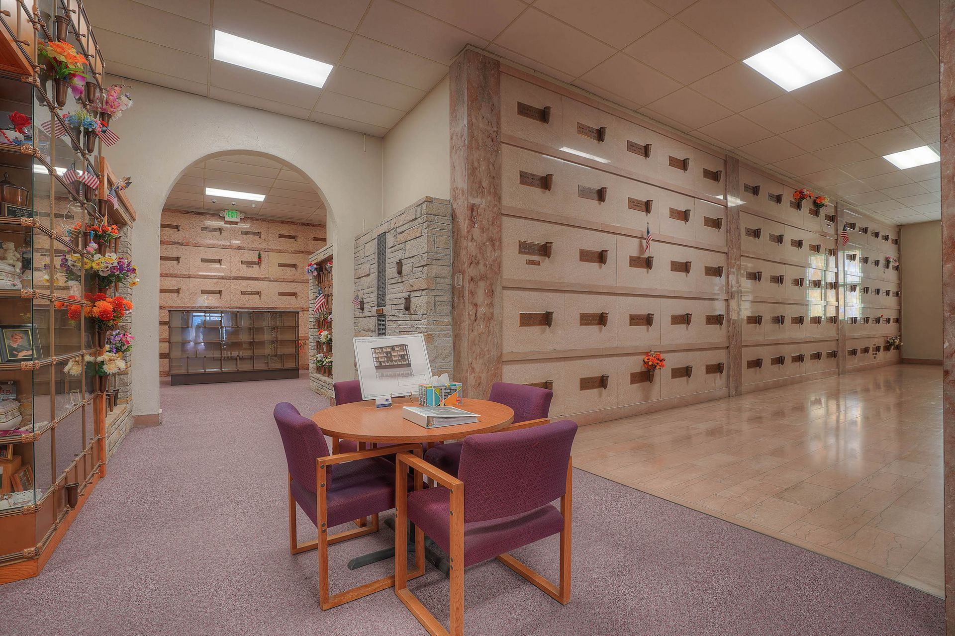 Mailroom lobby with purple chairs, a small table, and wall-mounted mailboxes under bright ceiling lights