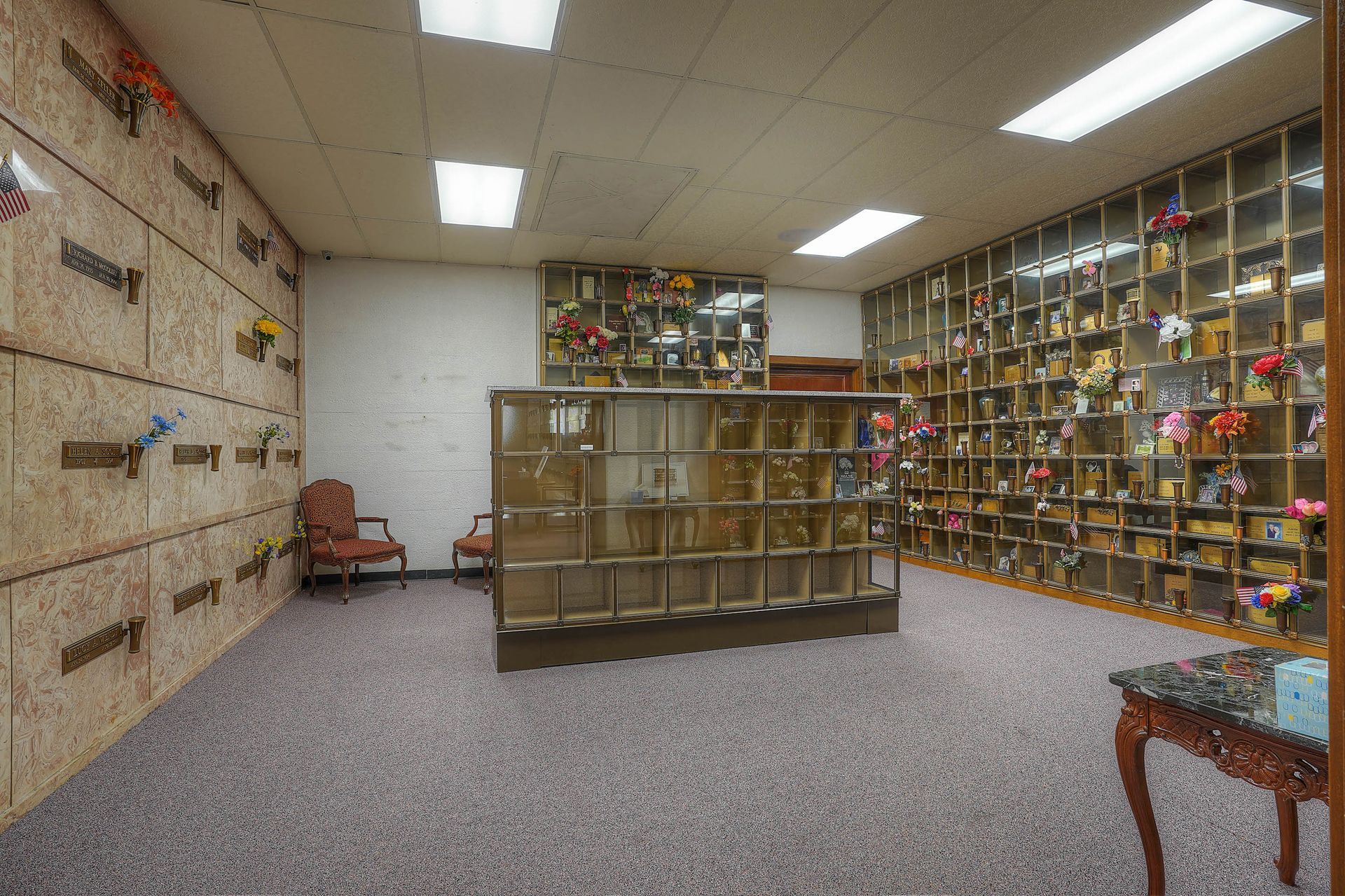 Empty library room with bookshelves on the right, wall shelves on the left, and carpeted floor.