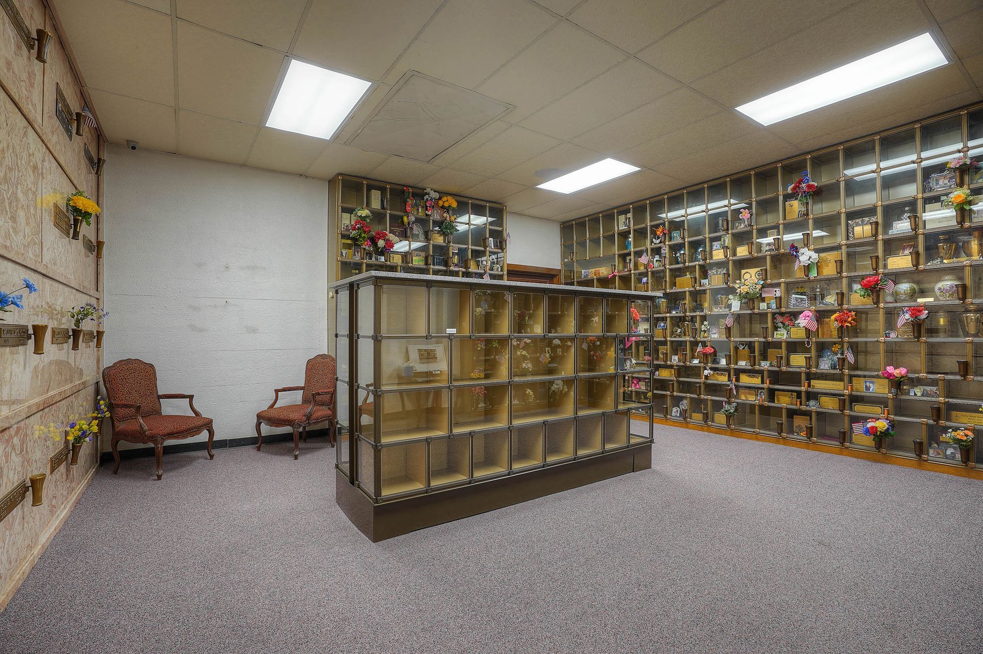 Library room with bookshelves, display cases, and two chairs under bright ceiling lights