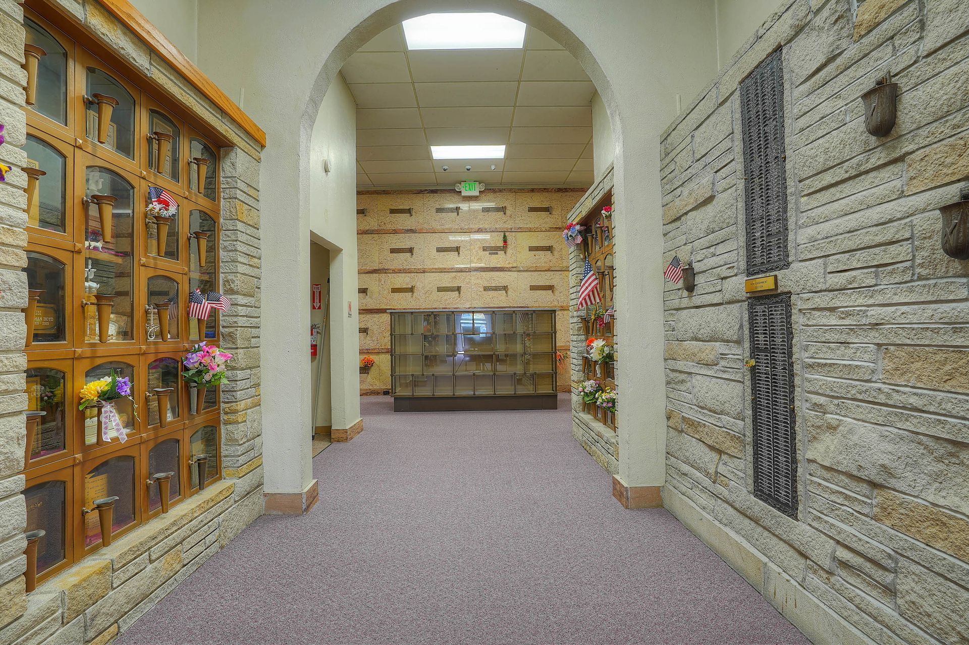 Quiet indoor hallway with carpet, wall niches, and a glass display cabinet on the left.