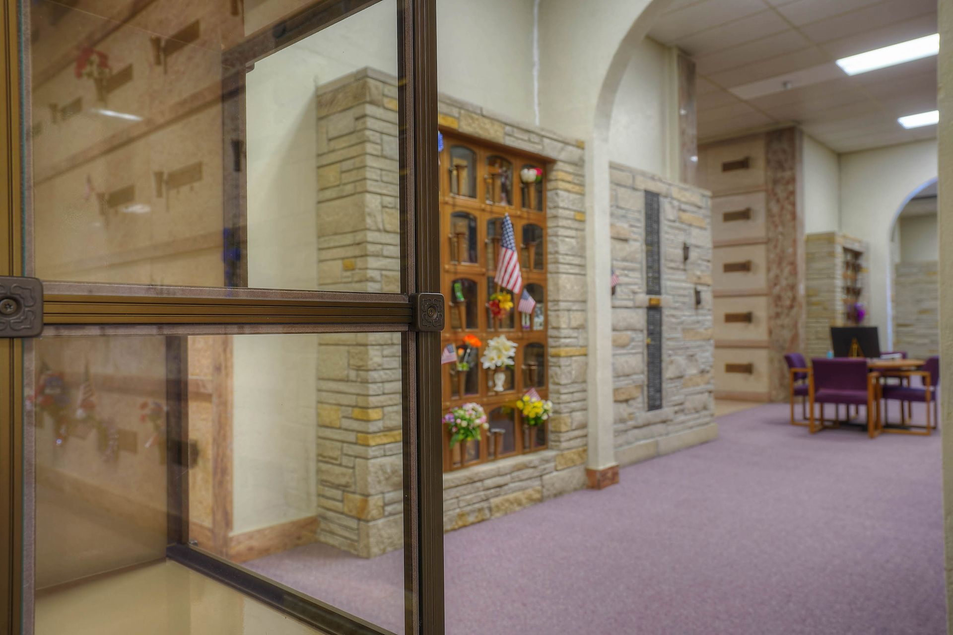 Library hallway with glass doors, book display, and seating area on purple carpet