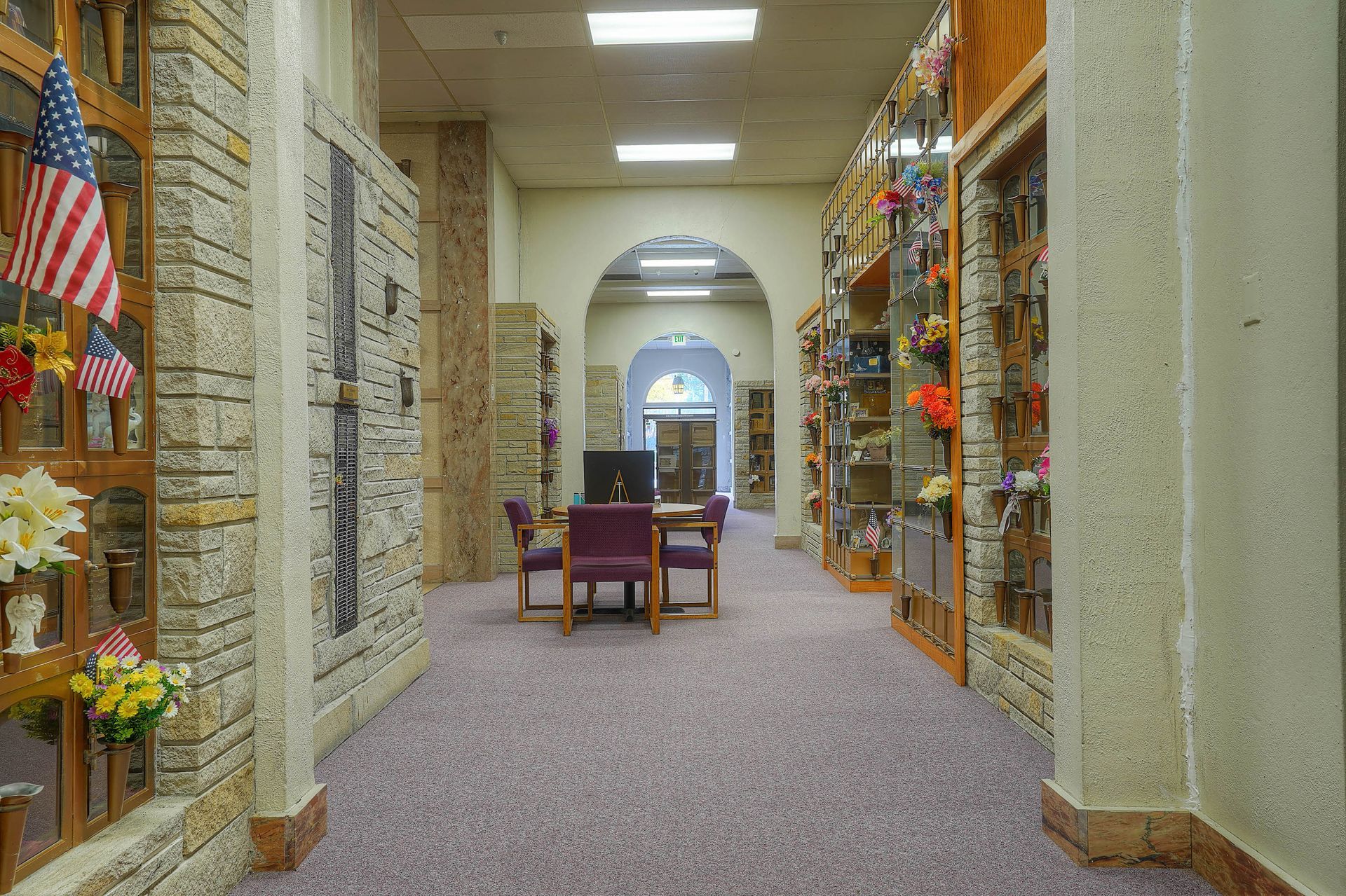 Library hallway with bookshelves, American flags, and chairs under arched ceilings