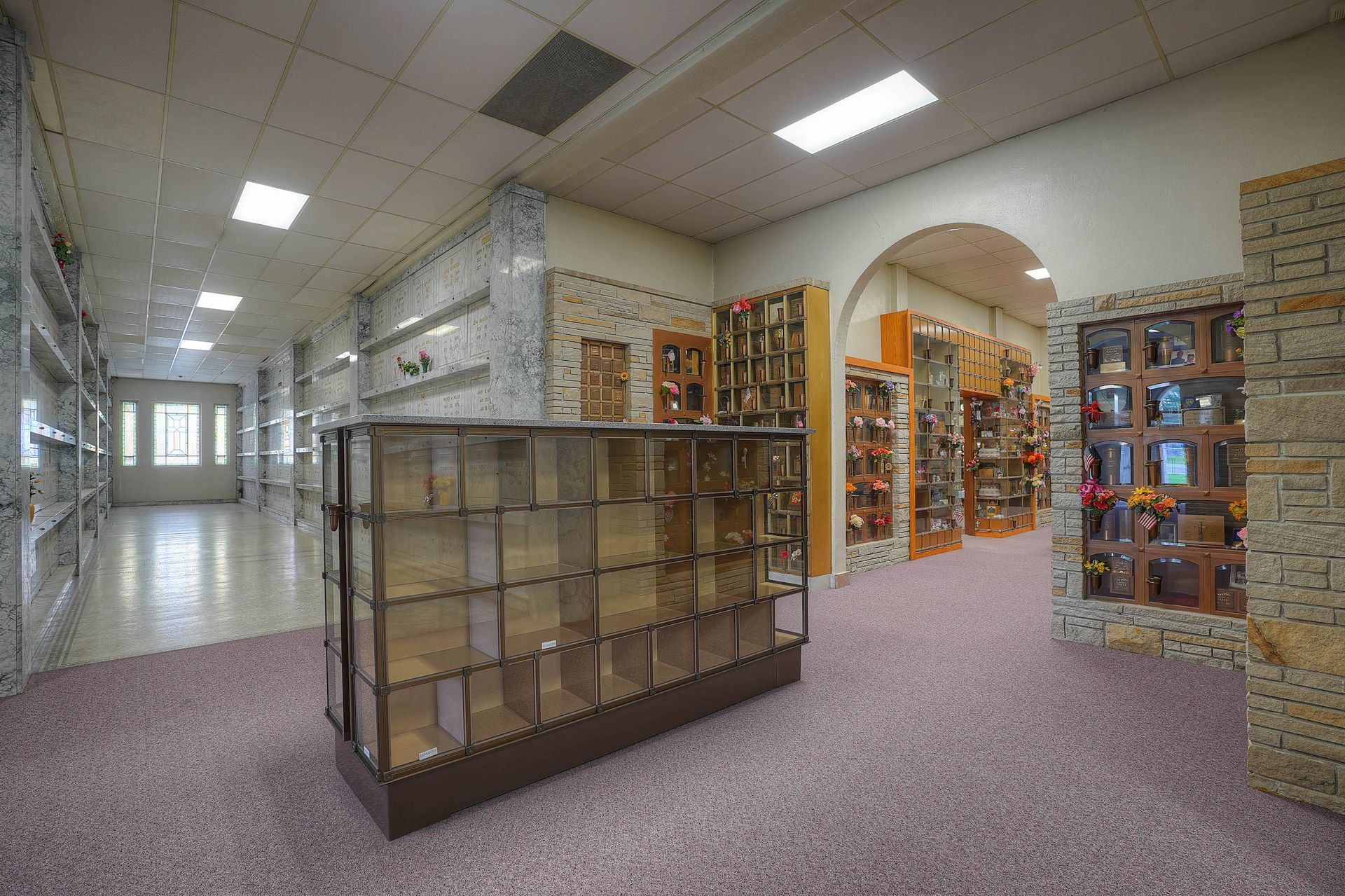 Library interior with bookshelves, display cases, and arched doorway in a quiet hallway