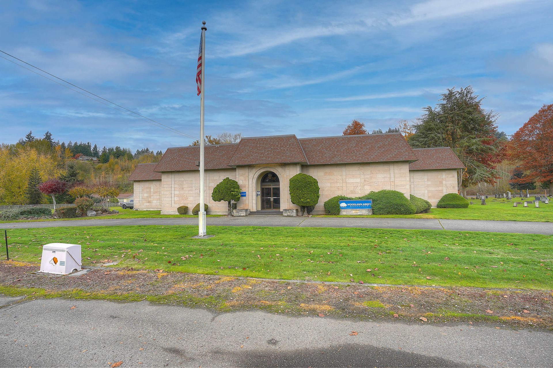 Single-story stone building with arches and an American flag in front on a grassy lawn