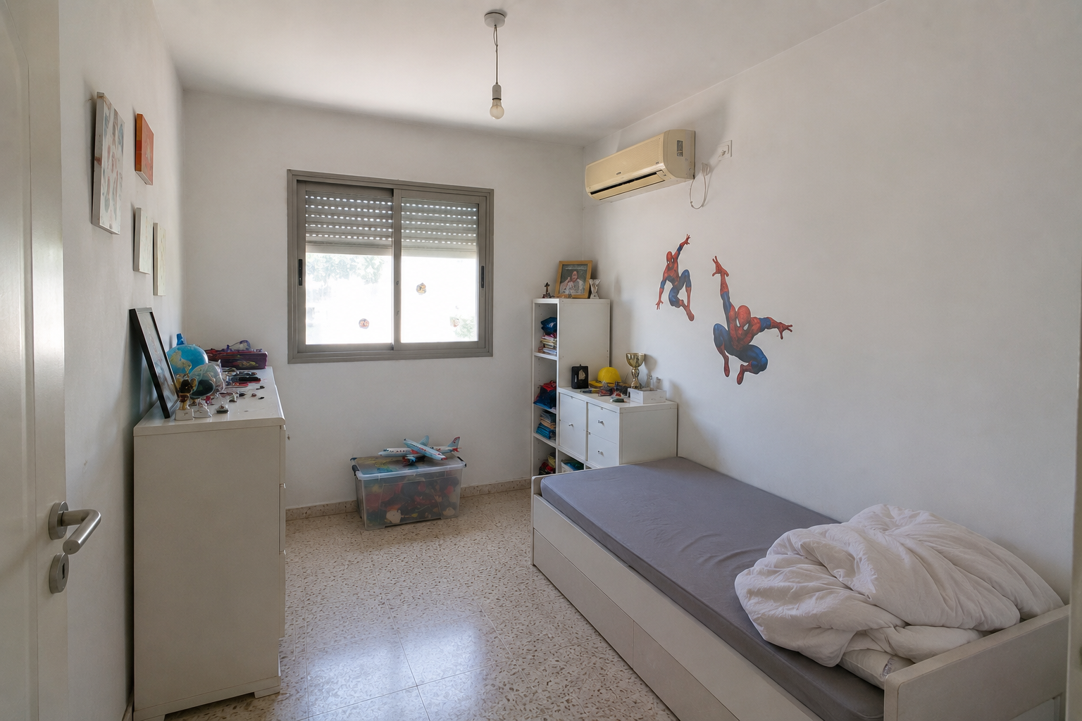 Small bedroom with a single bed, window, dresser, and children’s wall decals; air conditioner above the bed.