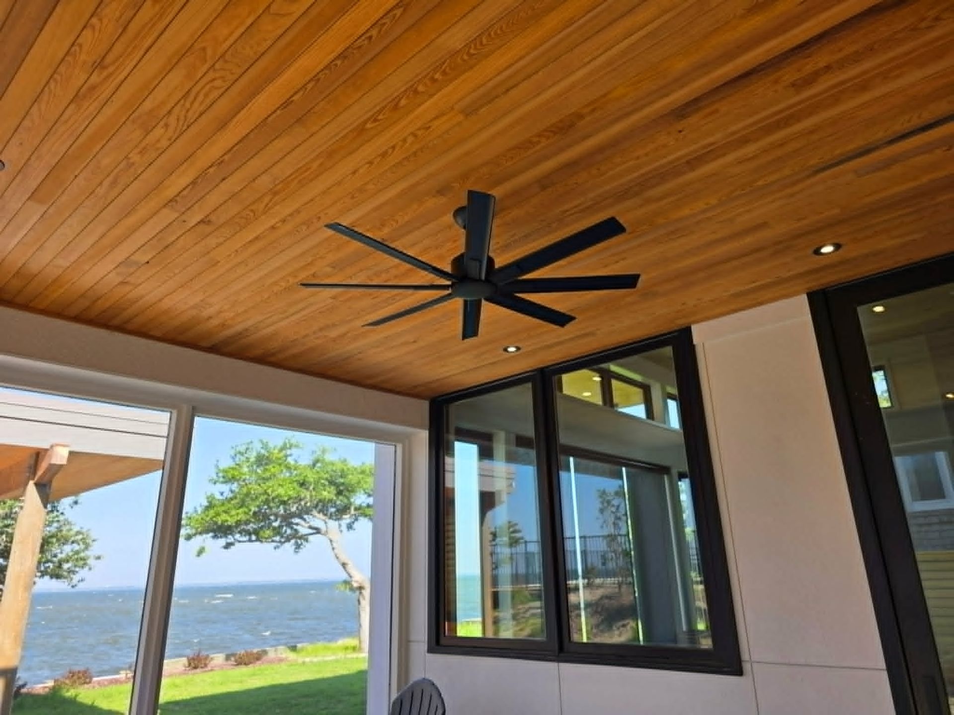 Outdoor ceiling fan and recessed lighting beneath a coastal wood ceiling by Shoreline Electric of KDH Outer Banks, NC
