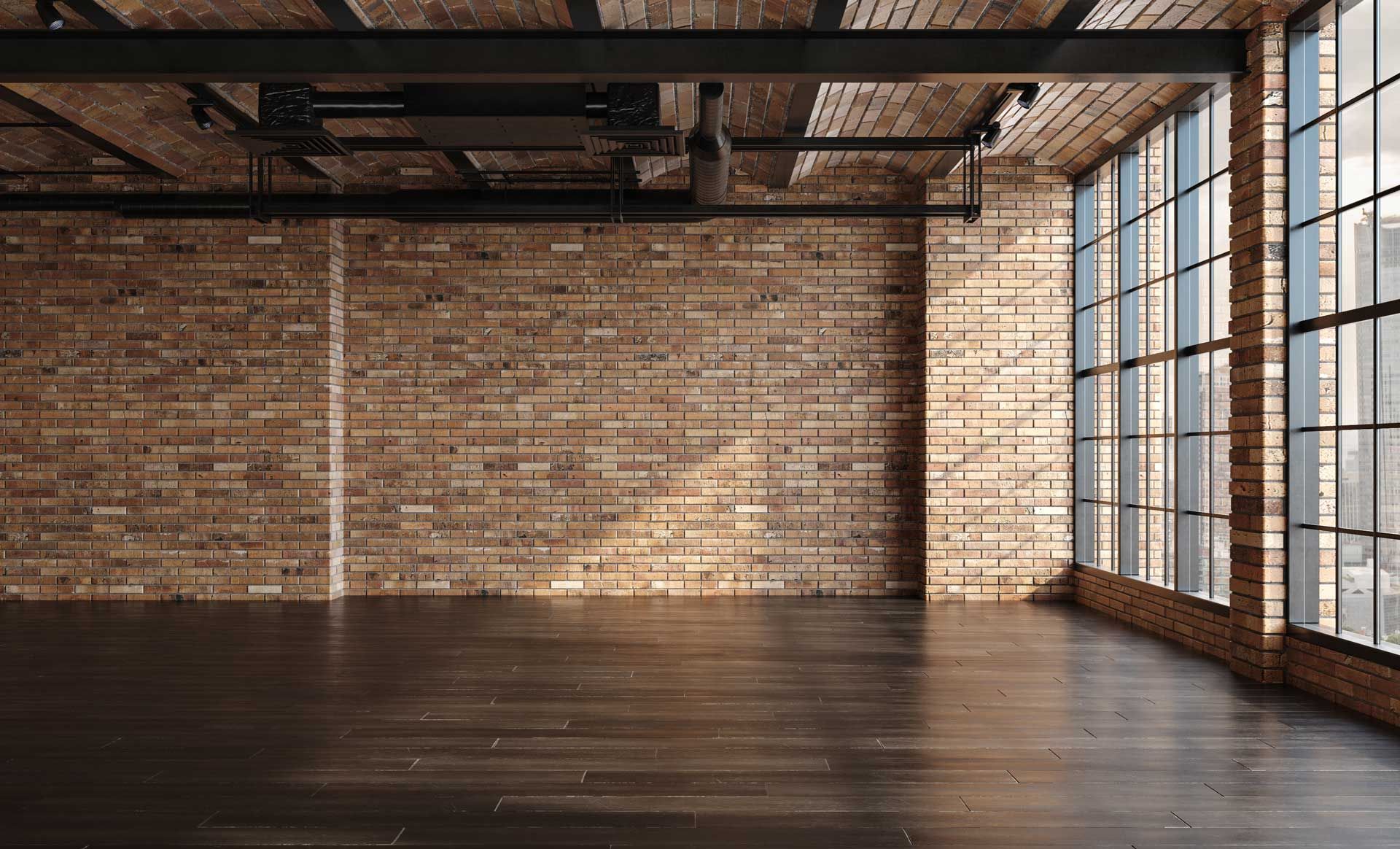 An empty room with a brick wall and lots of windows.