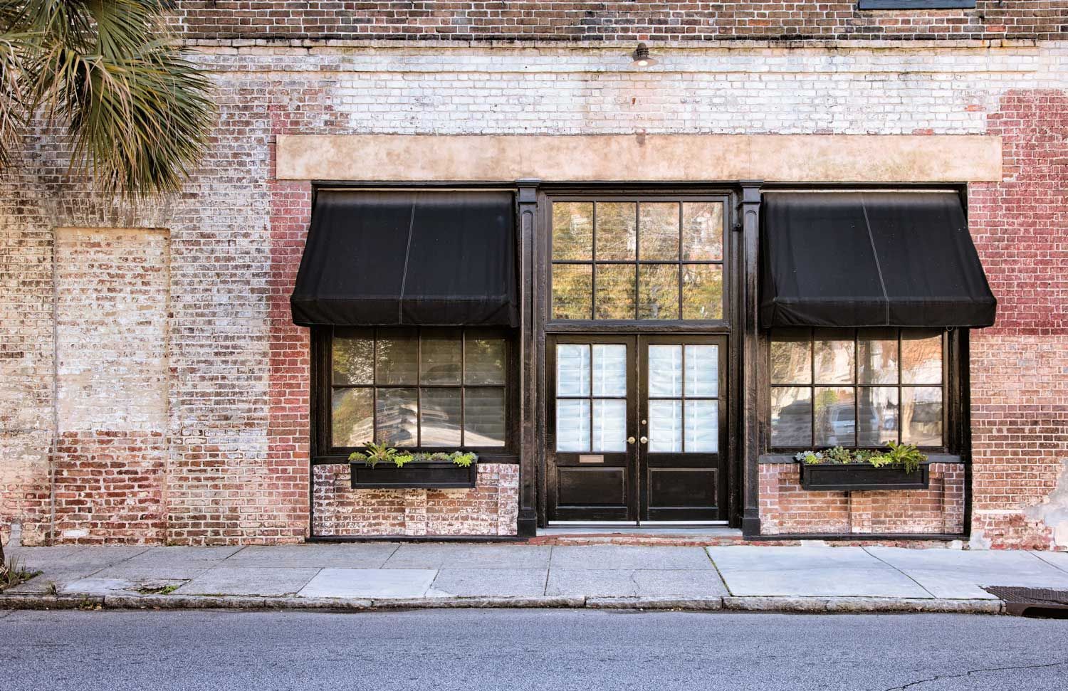 A brick building with black awnings on the windows and doors.