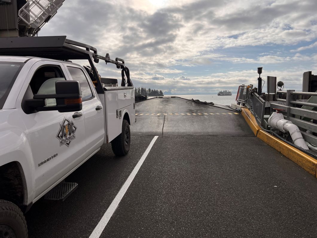 A white truck is parked on the side of a road next to a bridge.