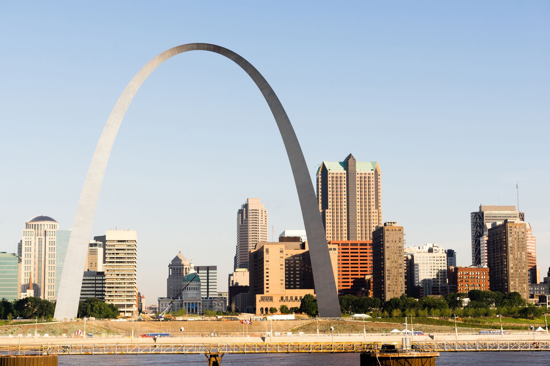 Gateway Arch, St. Louis, Missouri, spanning over a cityscape with high-rise buildings, blue sky.