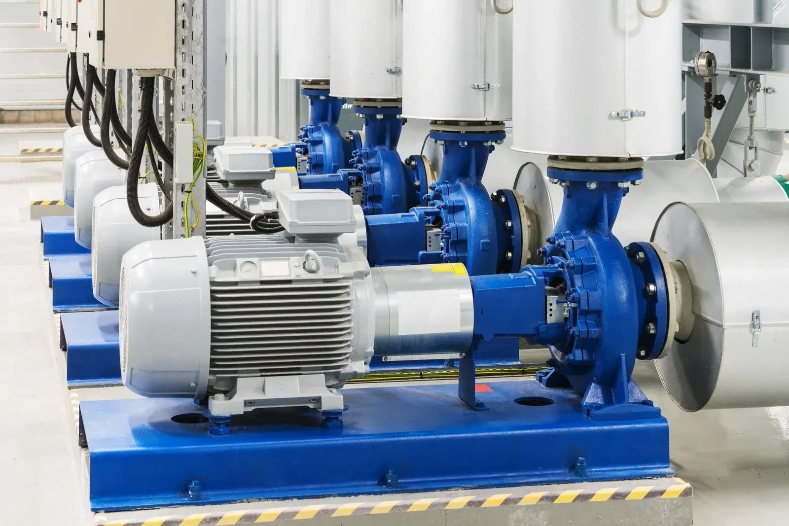 Row of industrial blue and silver pump motors in a factory setting