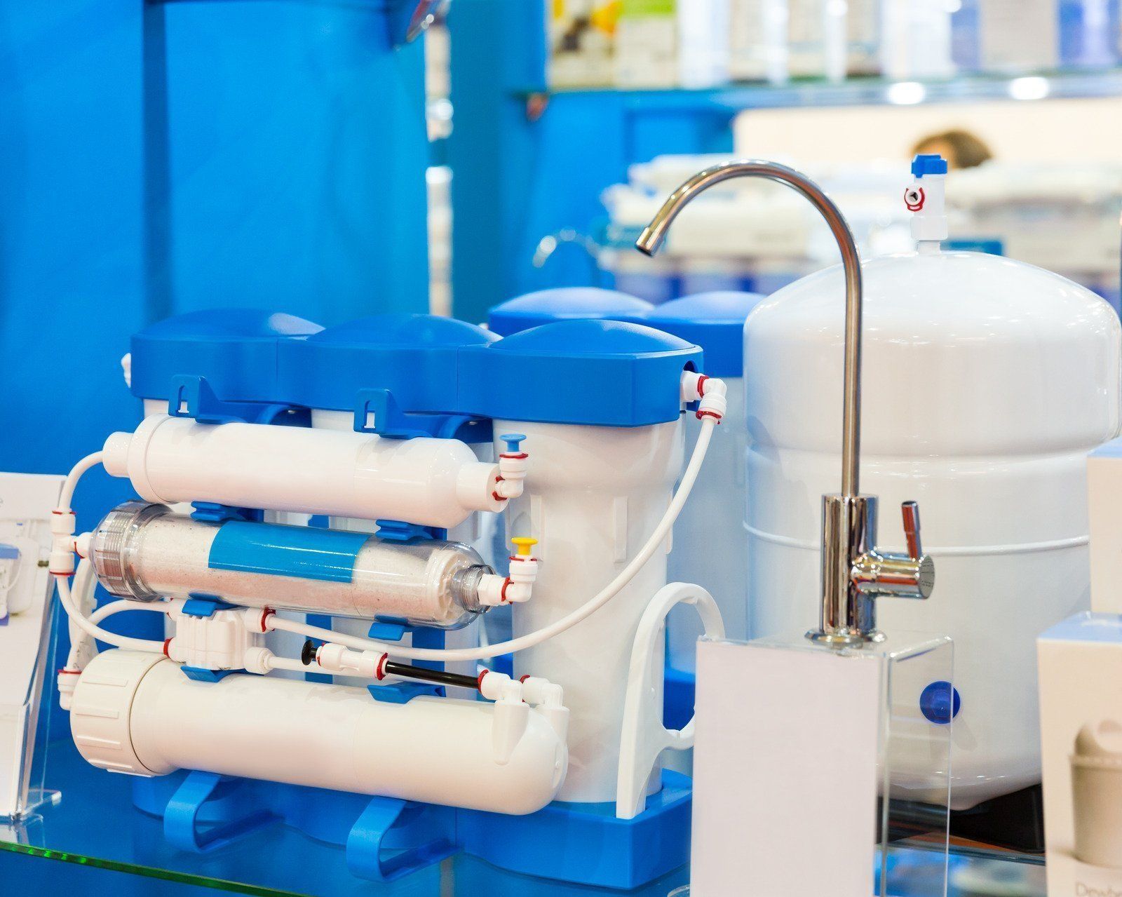 Blue-and-white water filtration system with tubes and a faucet in a lab setting